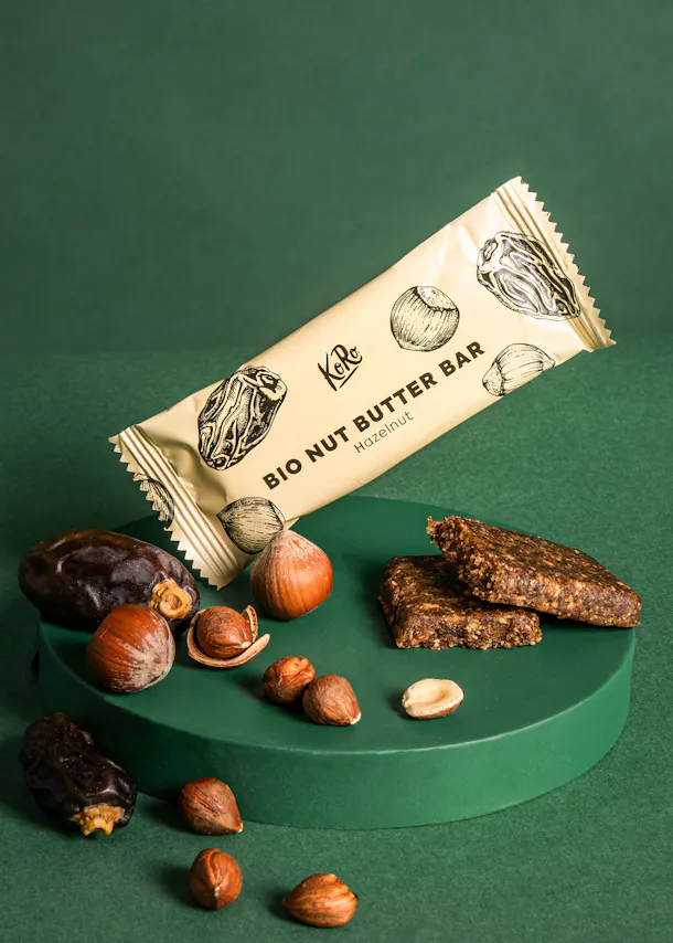une barre de beurre de noix bio est assise sur une table entourée de noix