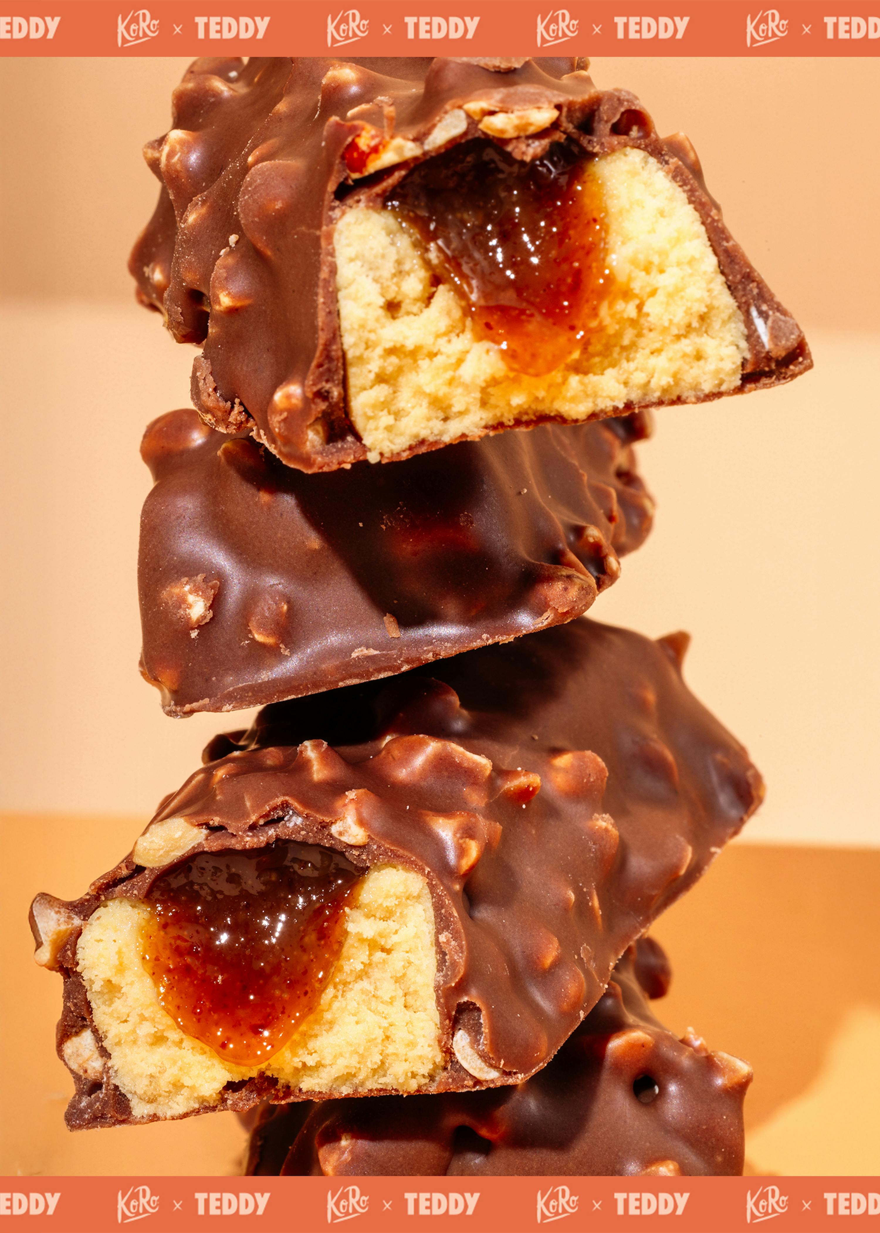 une pile de barres chocolatées enrobées de noix, coupées pour révéler un intérieur de gâteau jaune et une garniture de confiture ambrée.