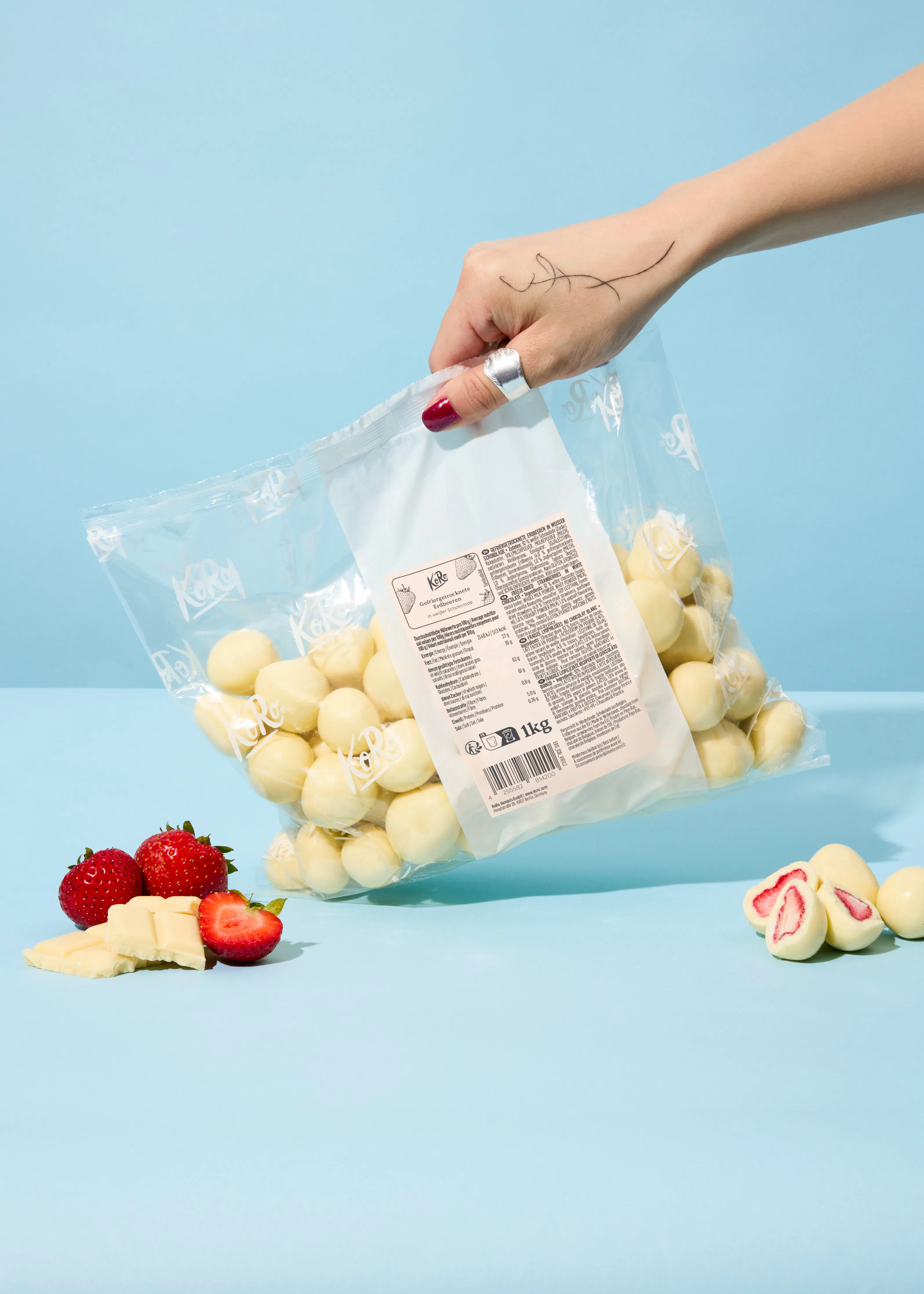 a woman is holding a bag of white chocolate covered strawberries