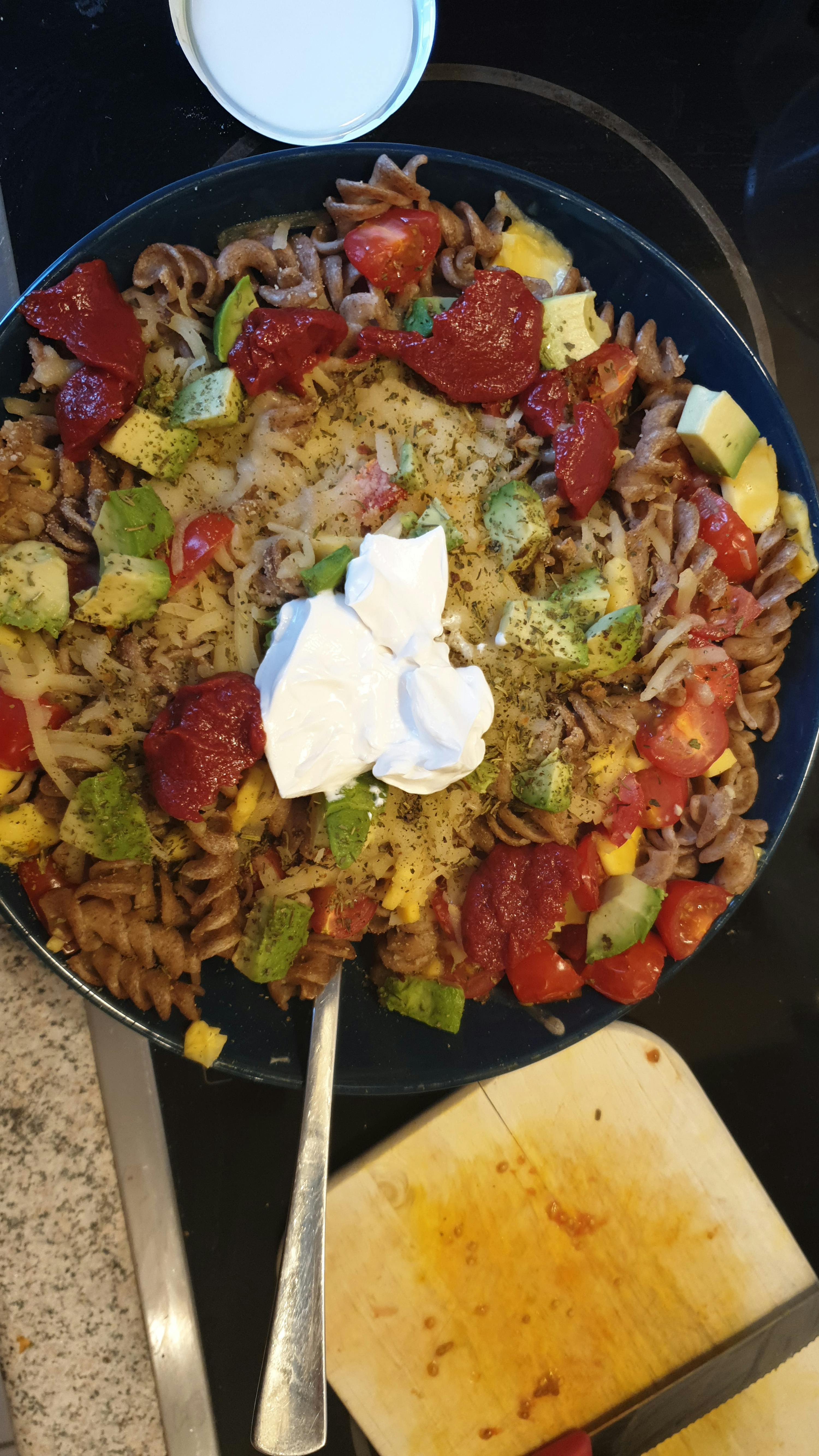 Eine Schüssel Nudeln mit Tomatensauce und Avocado auf einem Herd