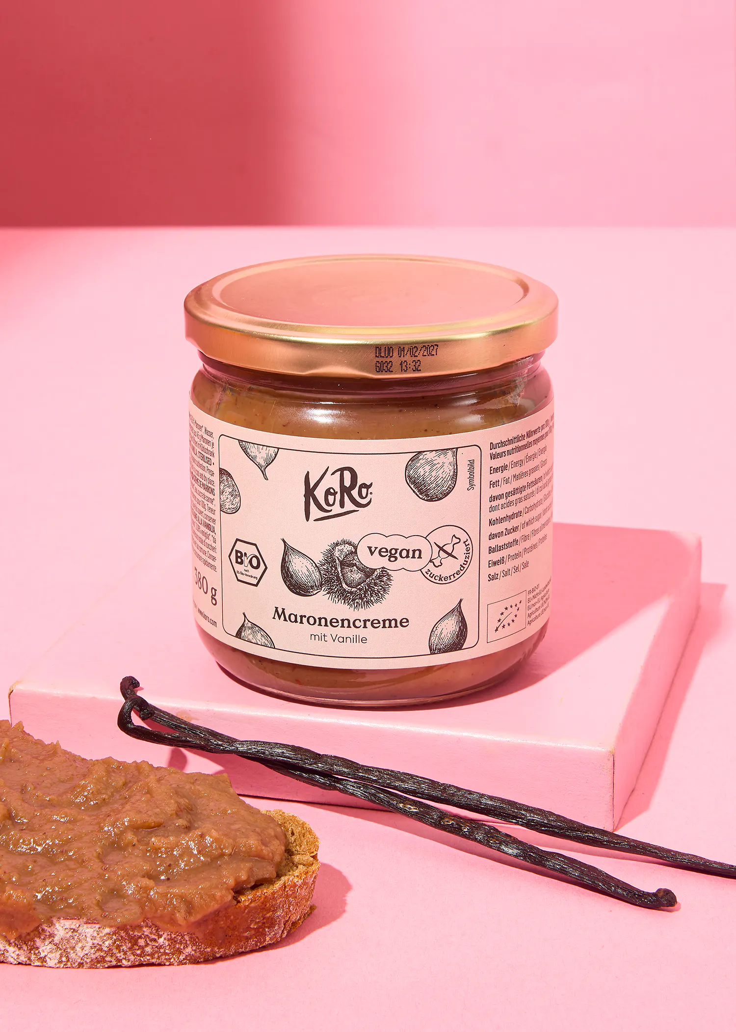 ein Glas maronencreme steht auf einem rosa Tisch neben einem Stück Brot