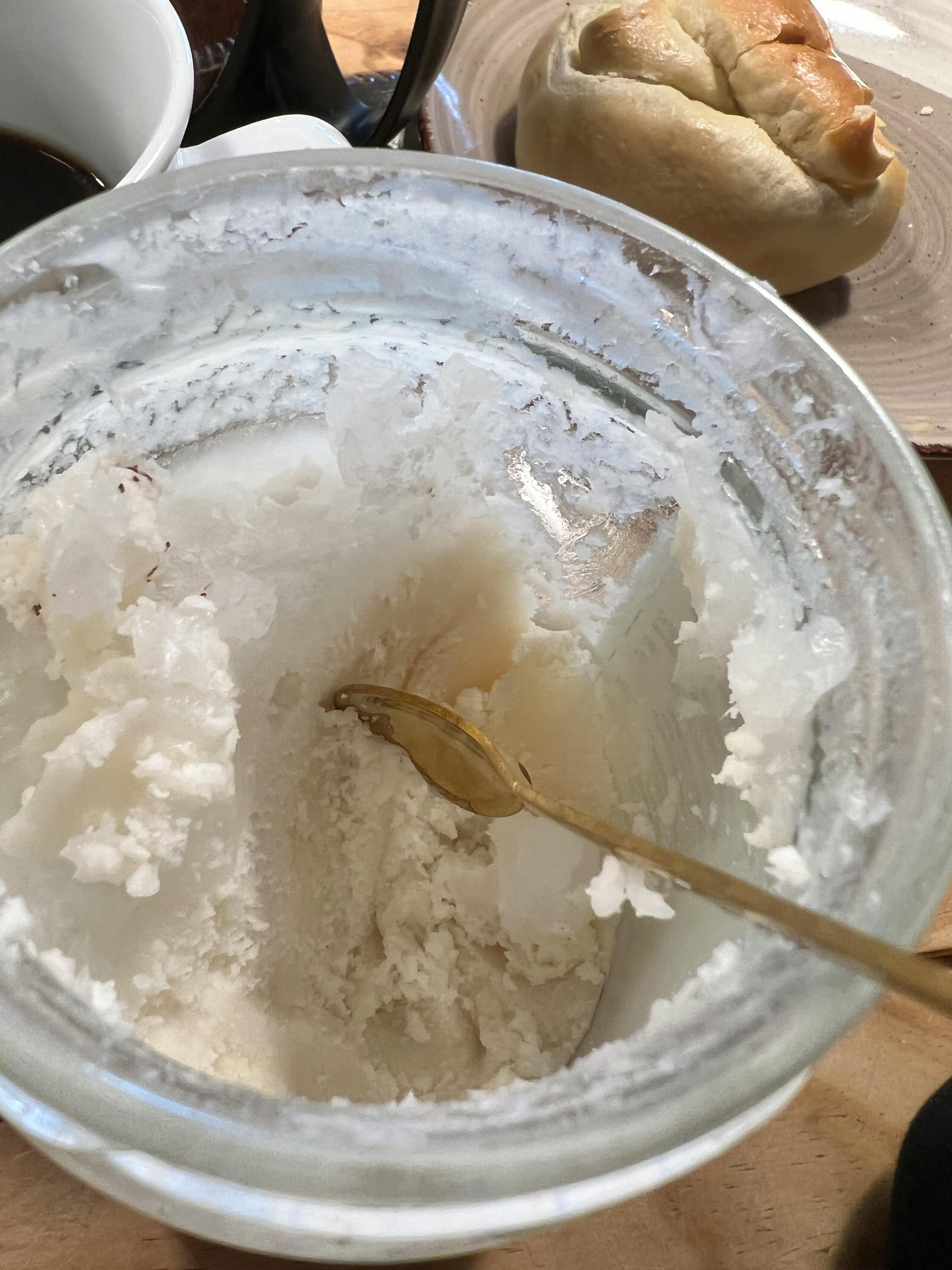 ein Glas mit einem Löffel darin und einem Brötchen darauf