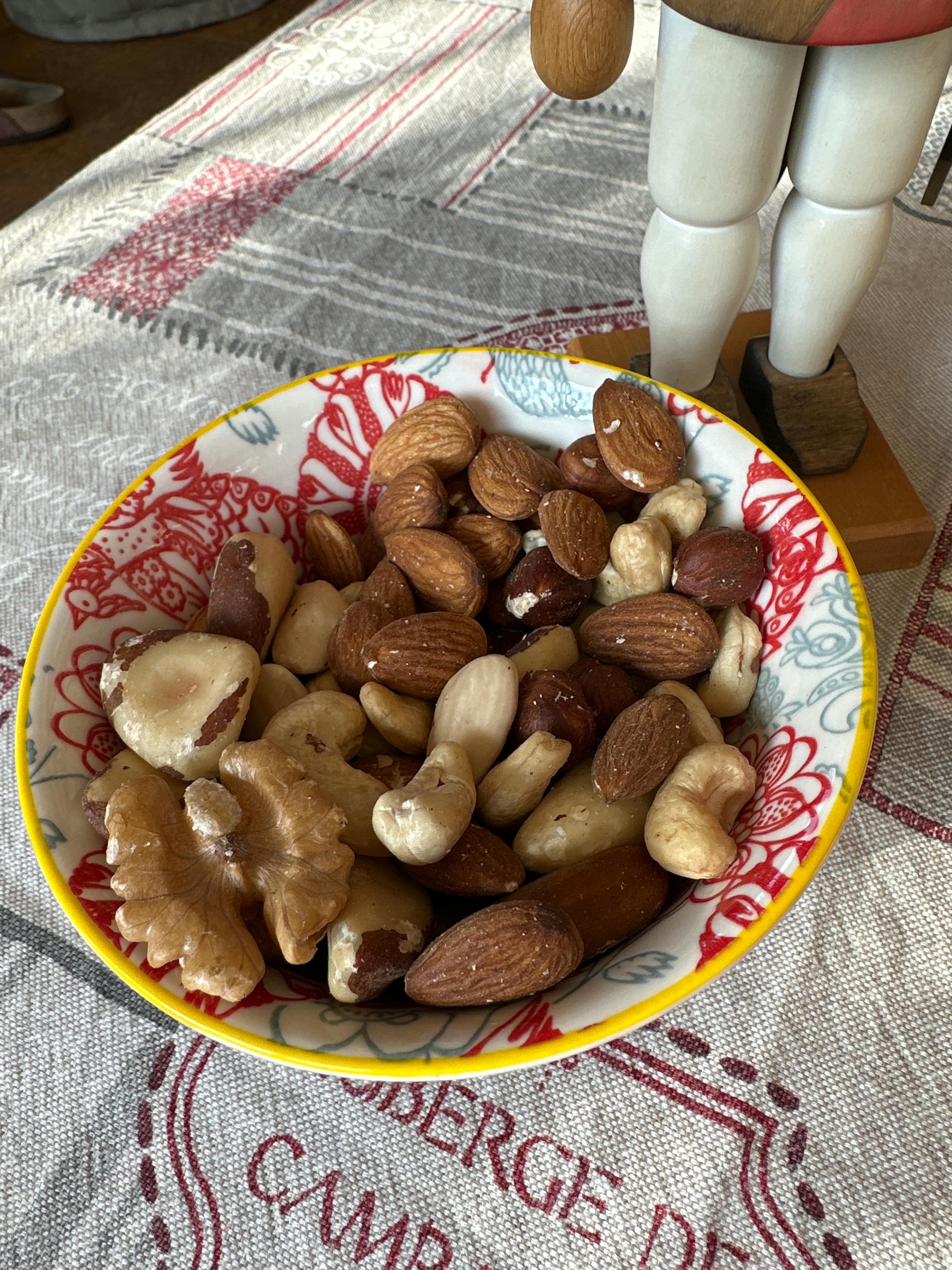 un bol rempli de noix sur une table avec une nappe à l' arrière qui dit camp