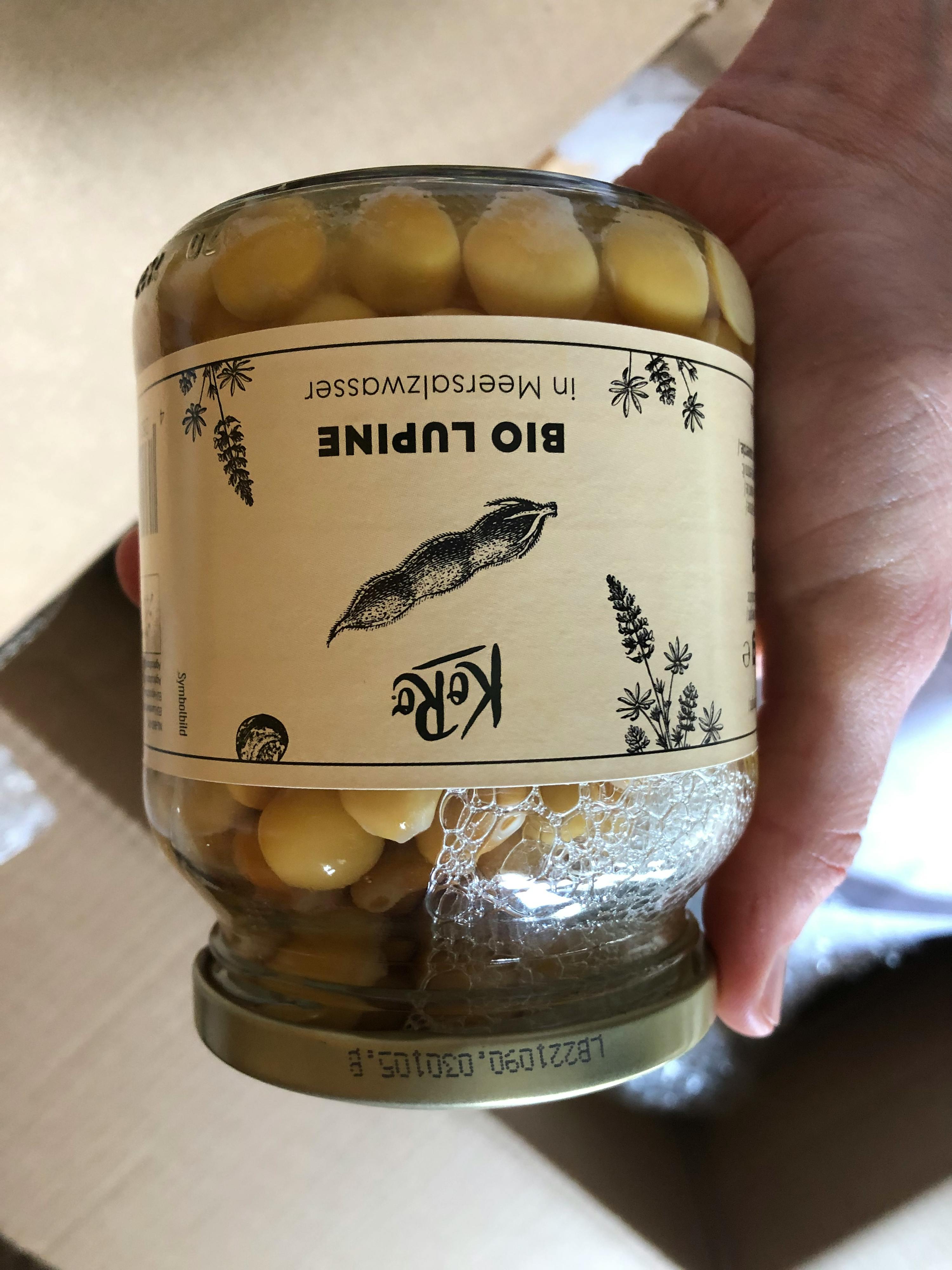 une personne tient un bocal de lupin bio dans l' eau de mer