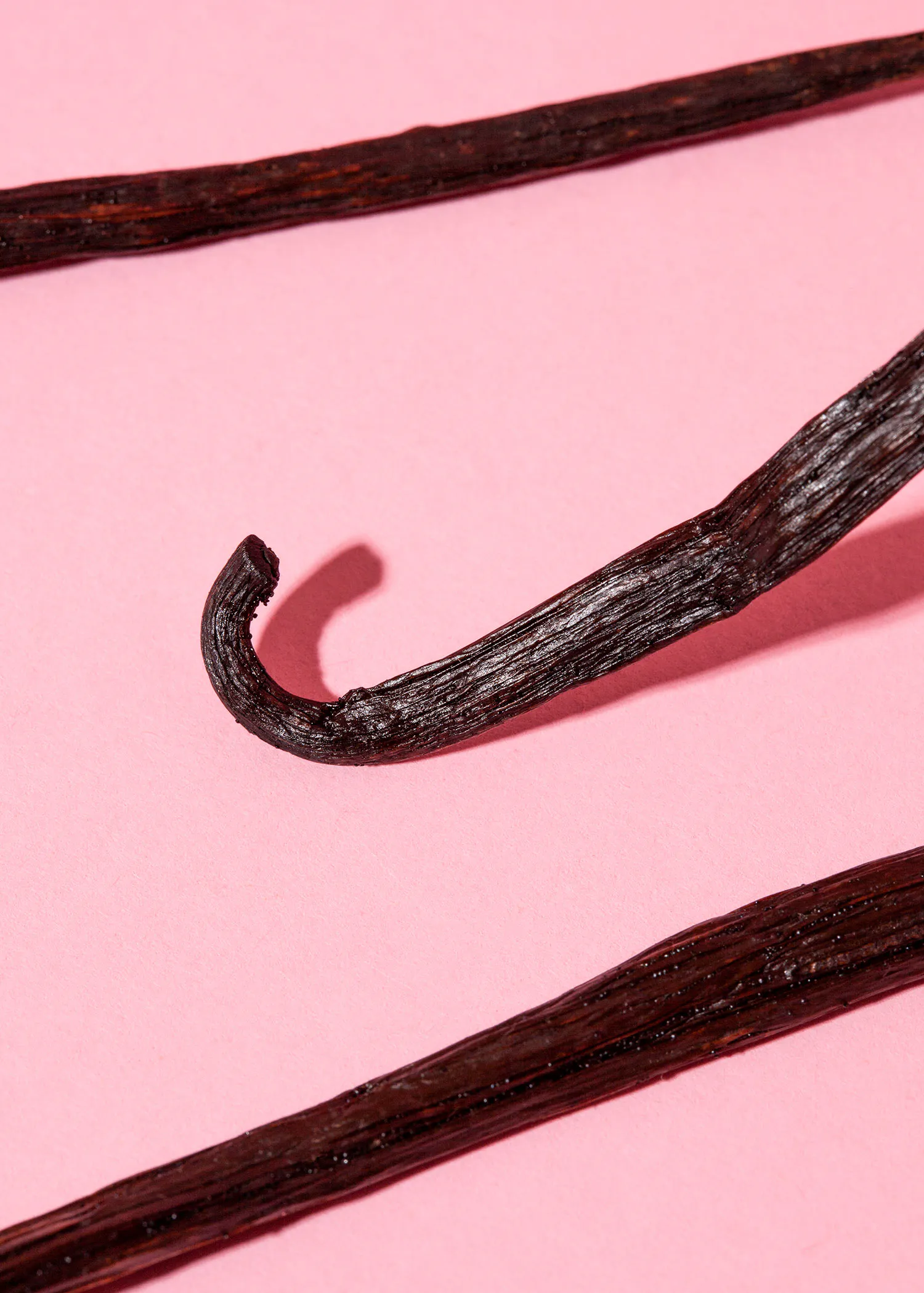 eine Nahaufnahme von Vanillestangen auf einem rosa Hintergrund
