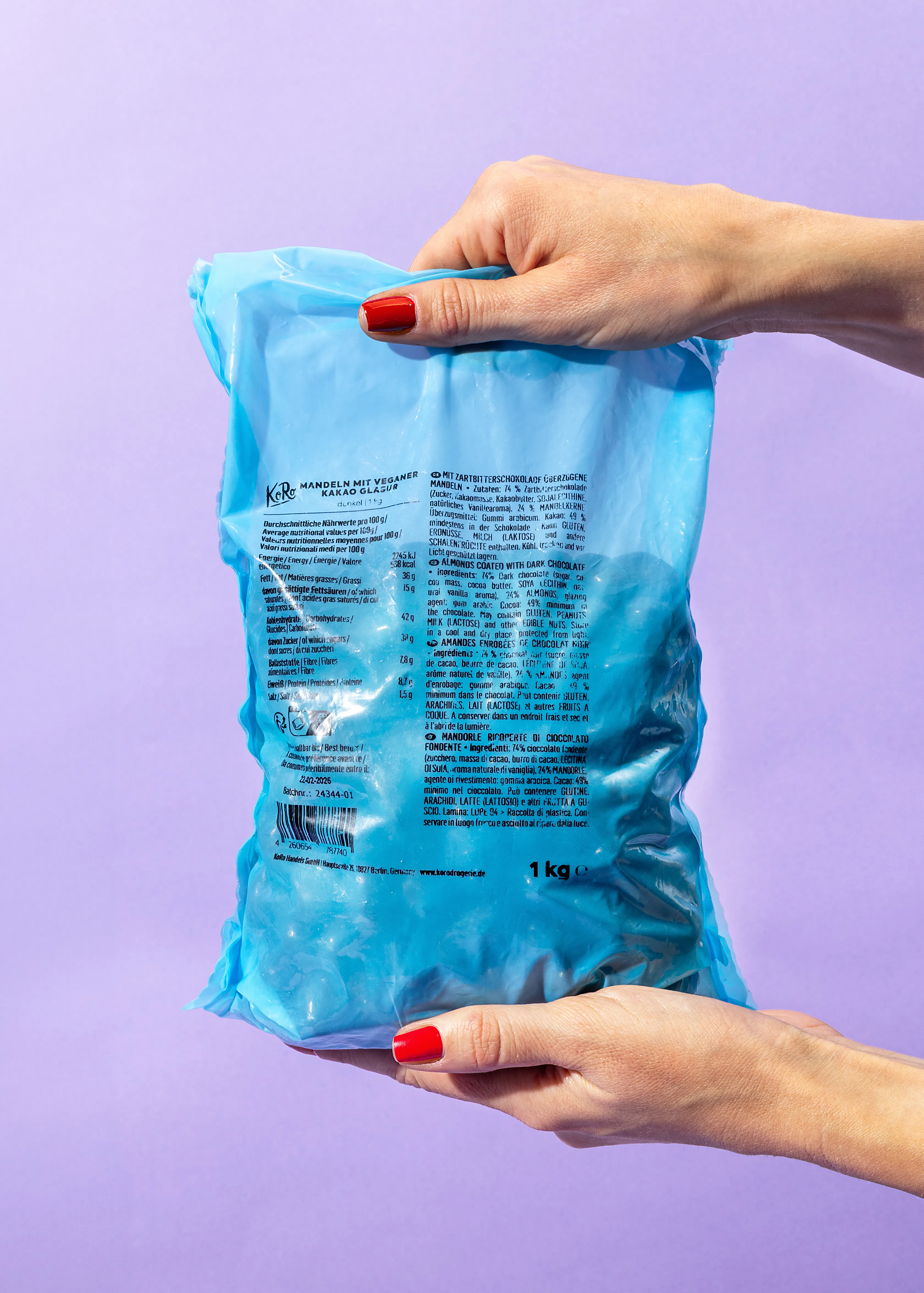 une personne tient un sac bleu de bonbons avec un arrière-plan violet