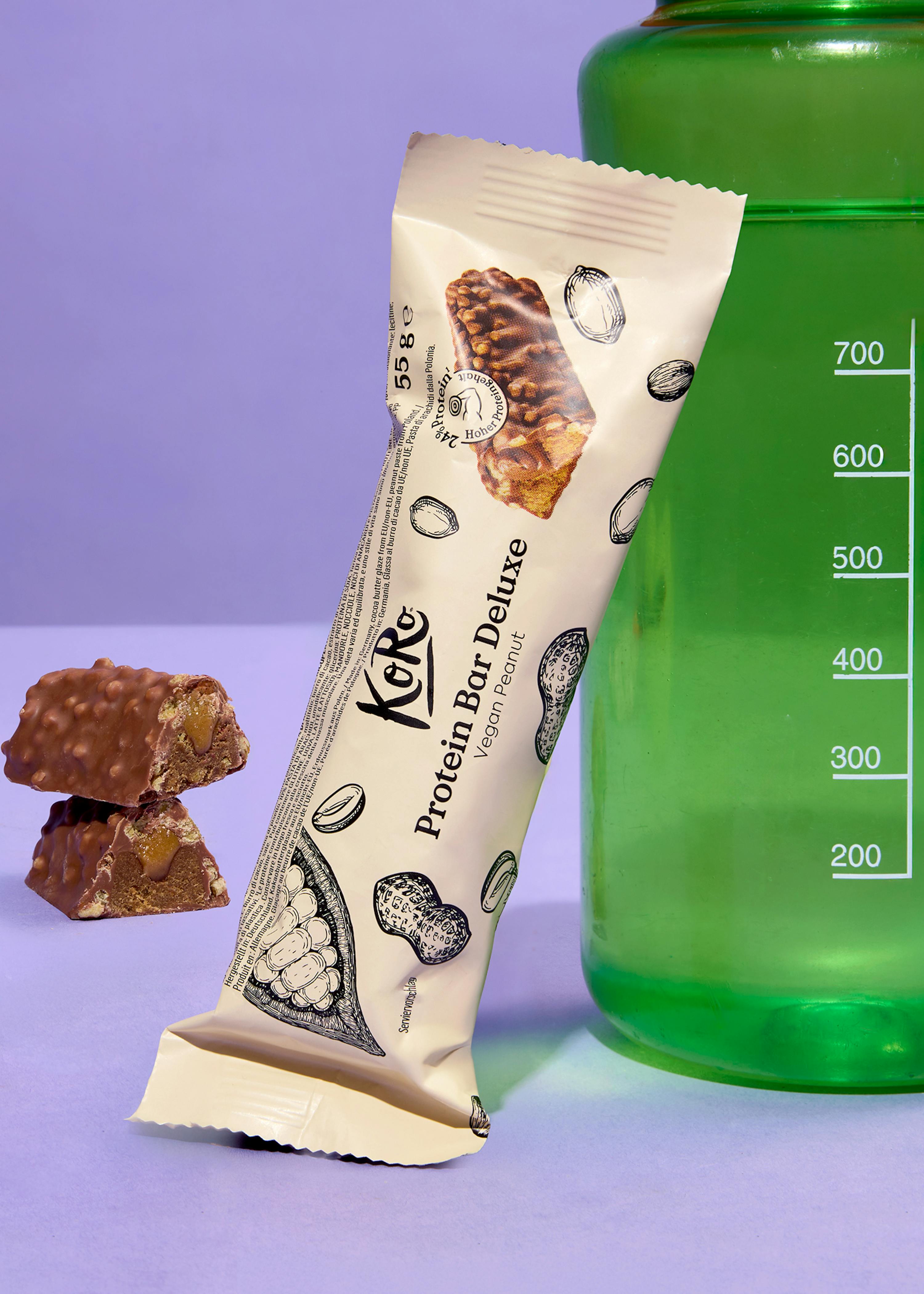 una barretta di proteine deluxe è seduta accanto a una bottiglia di acqua verde