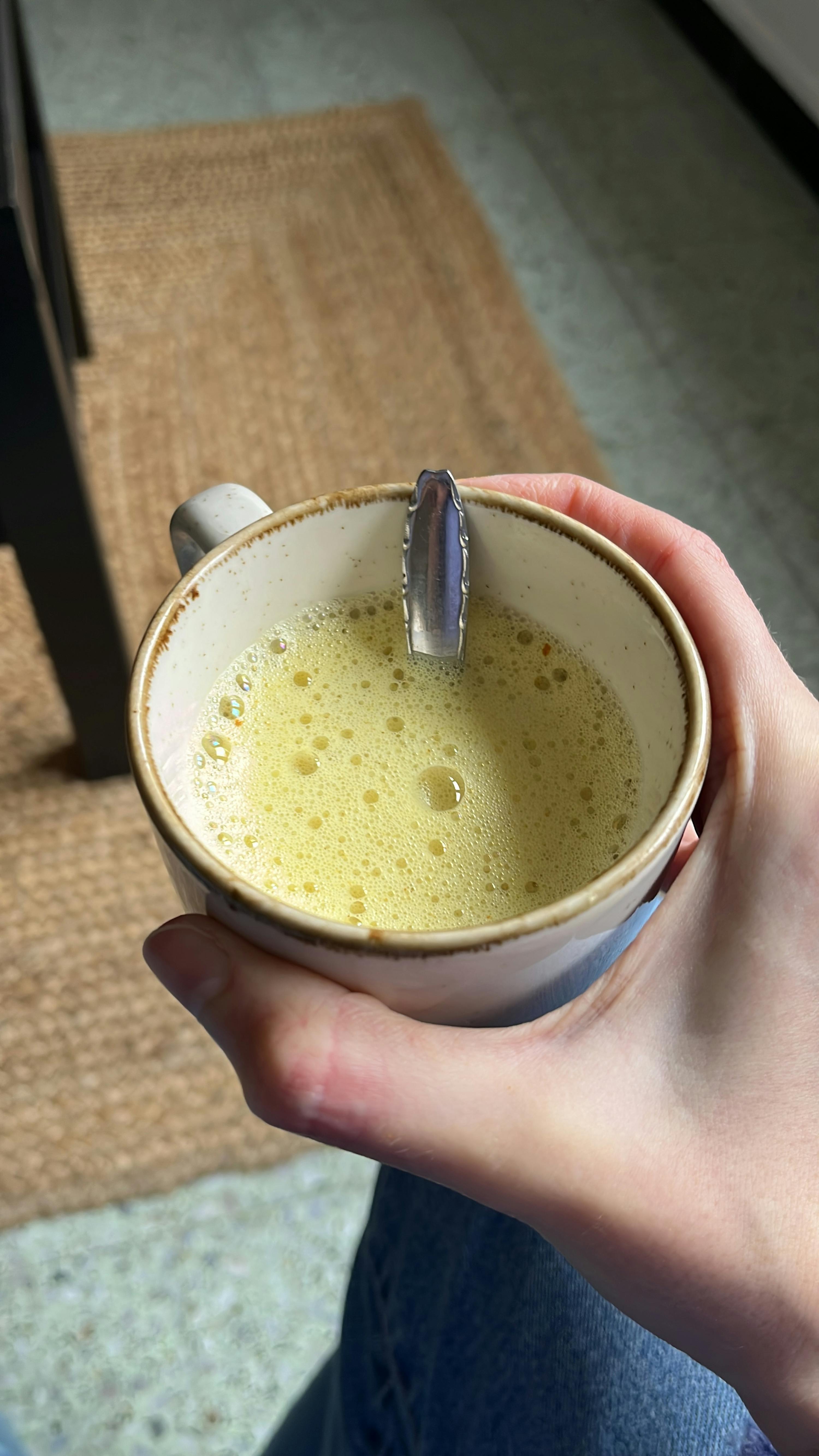 eine Person hält eine Tasse mit einem Löffel darin