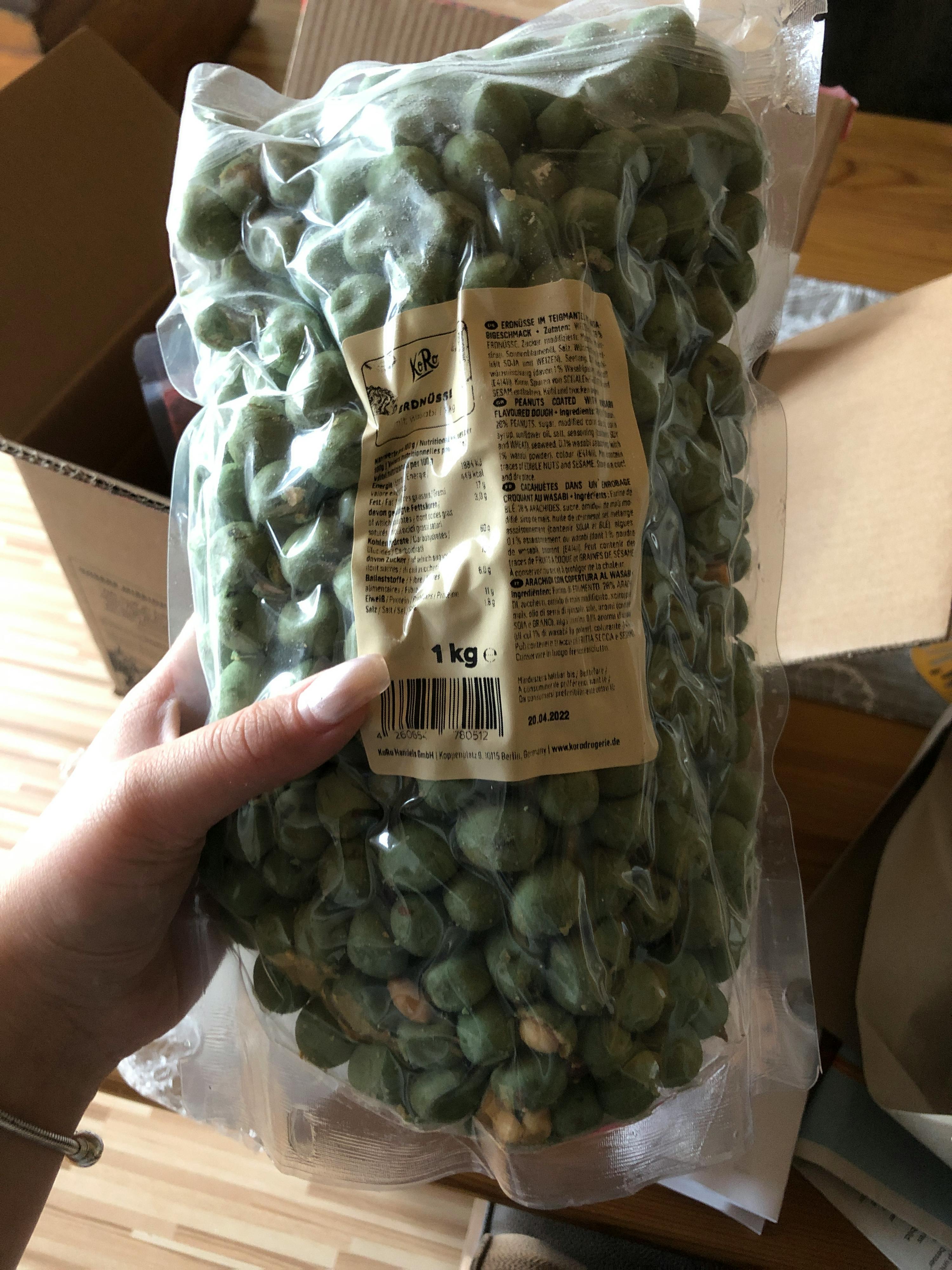 une personne tient un sac de cacahuètes vertes de 1kg