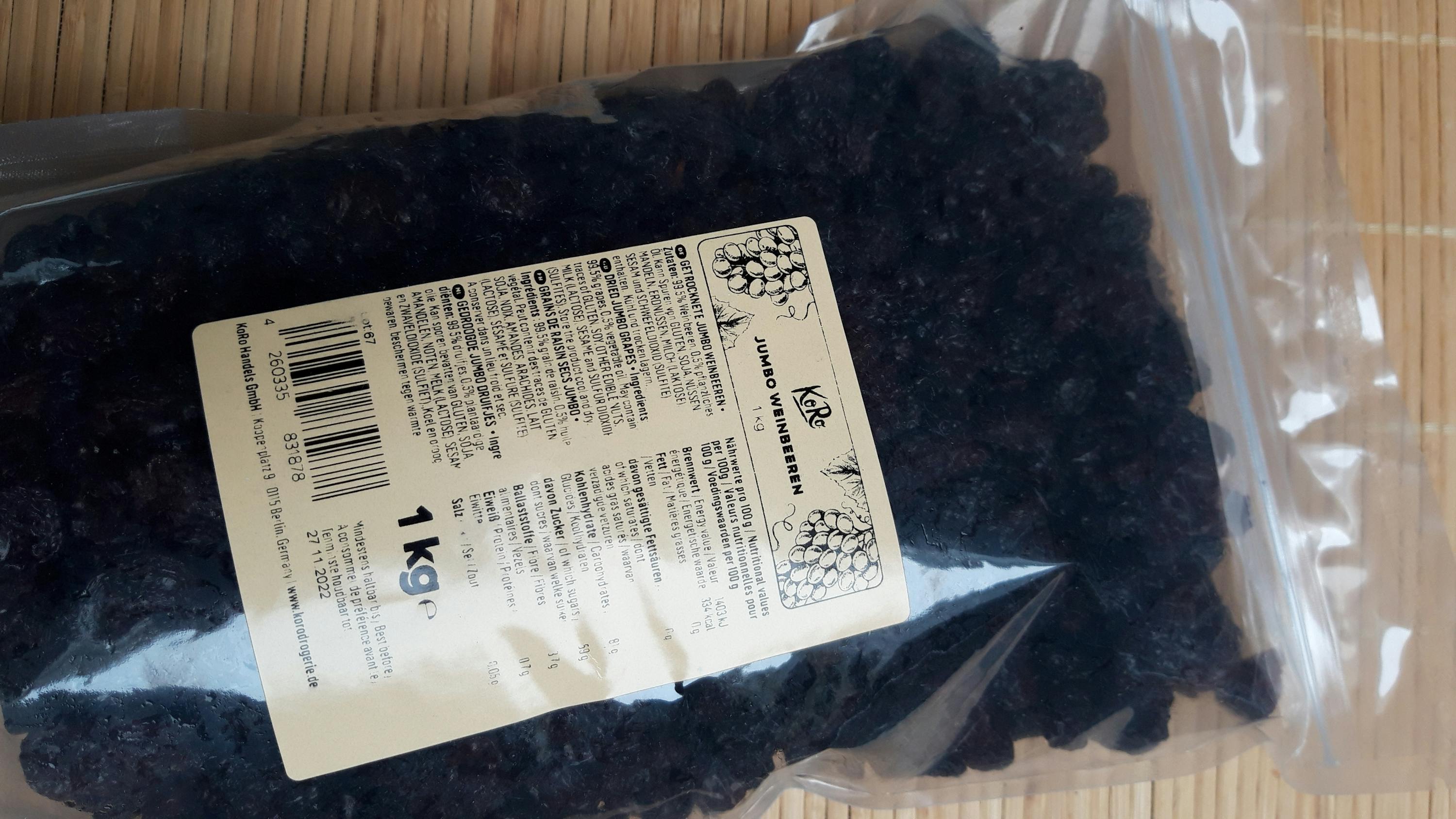 eine Plastiktüte mit schwarzen Rosinen steht auf einem Holztisch