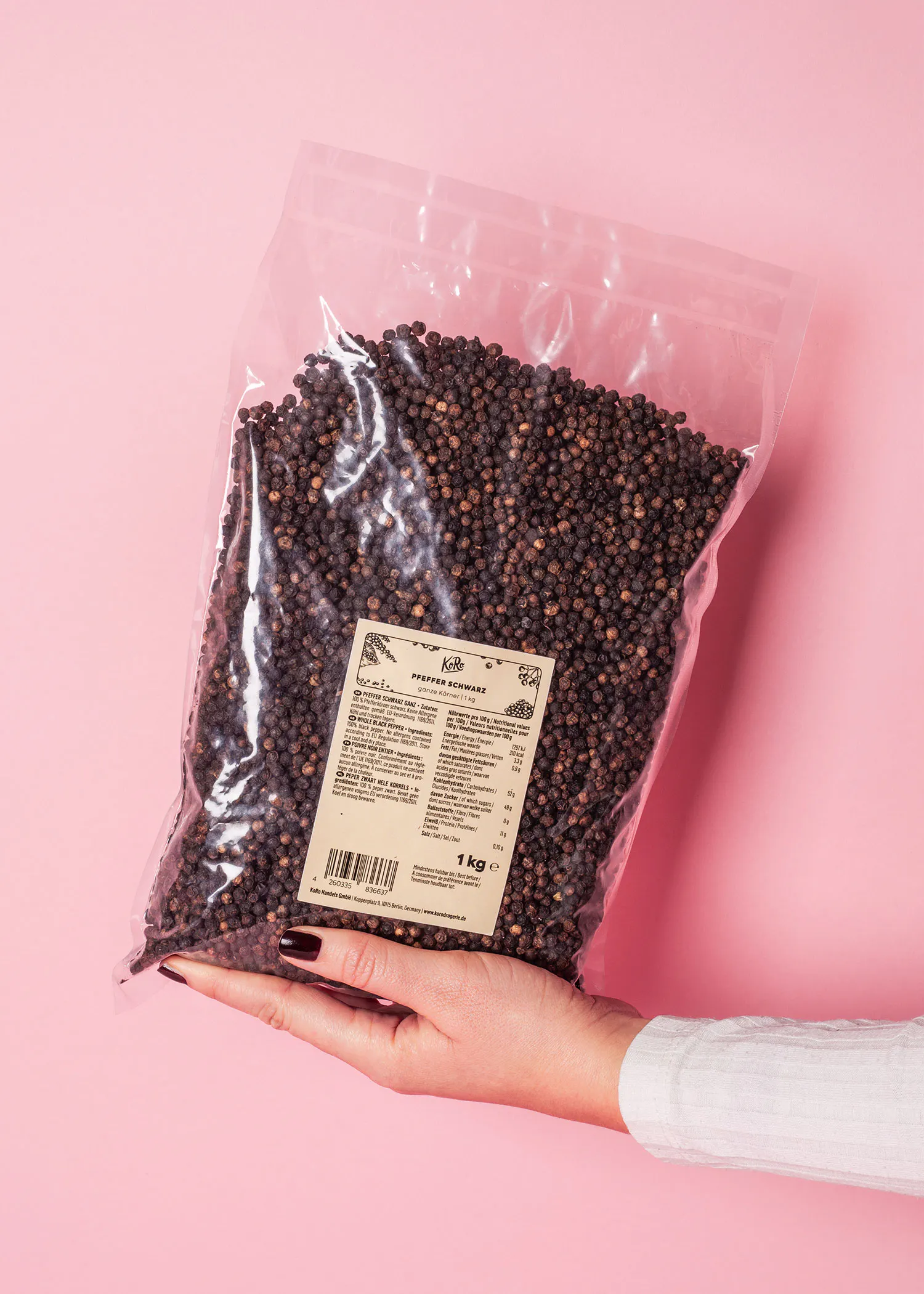 a person is holding a bag of black pepper with a label that says 1 kg