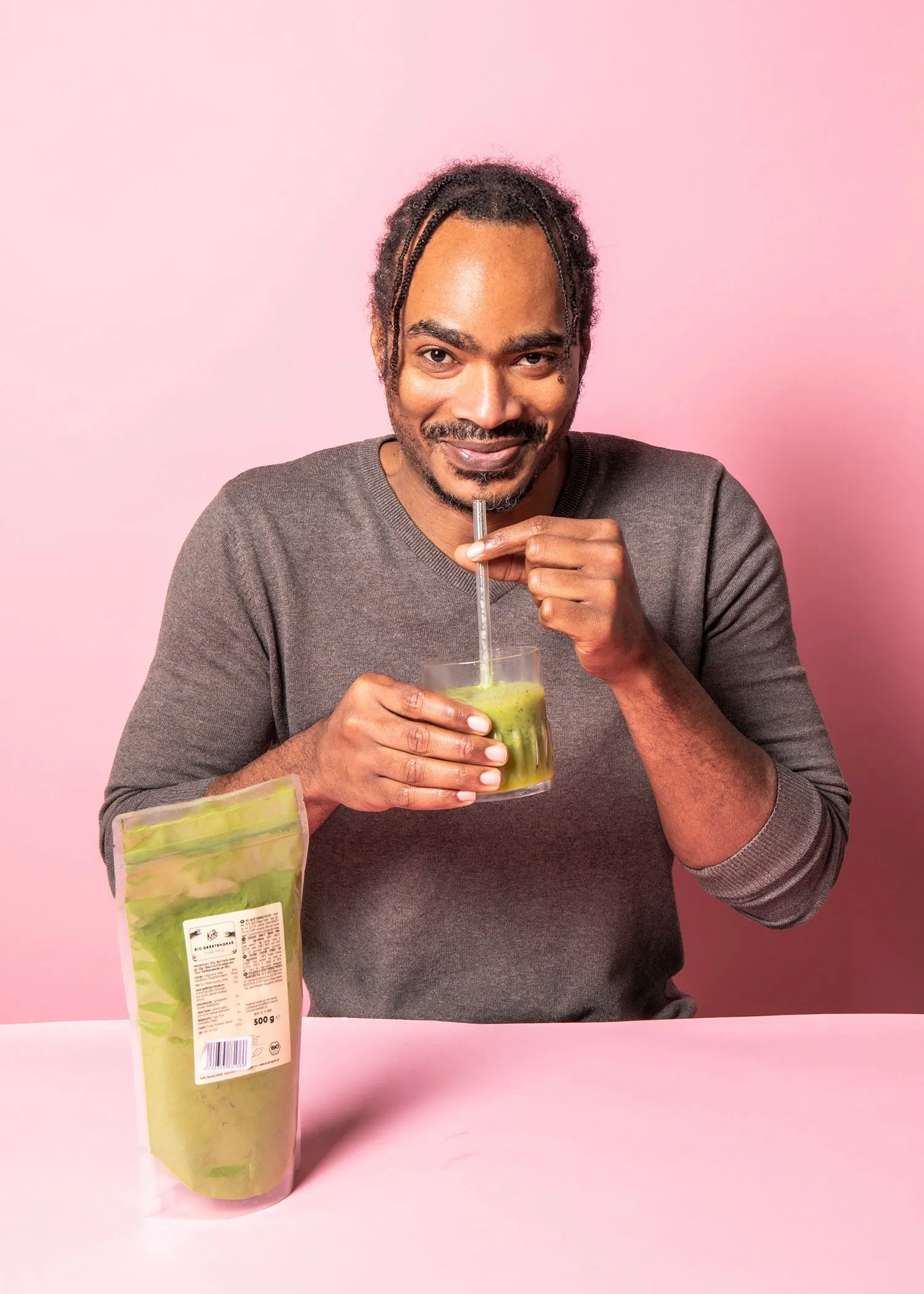 un homme boit un smoothie vert avec une paille