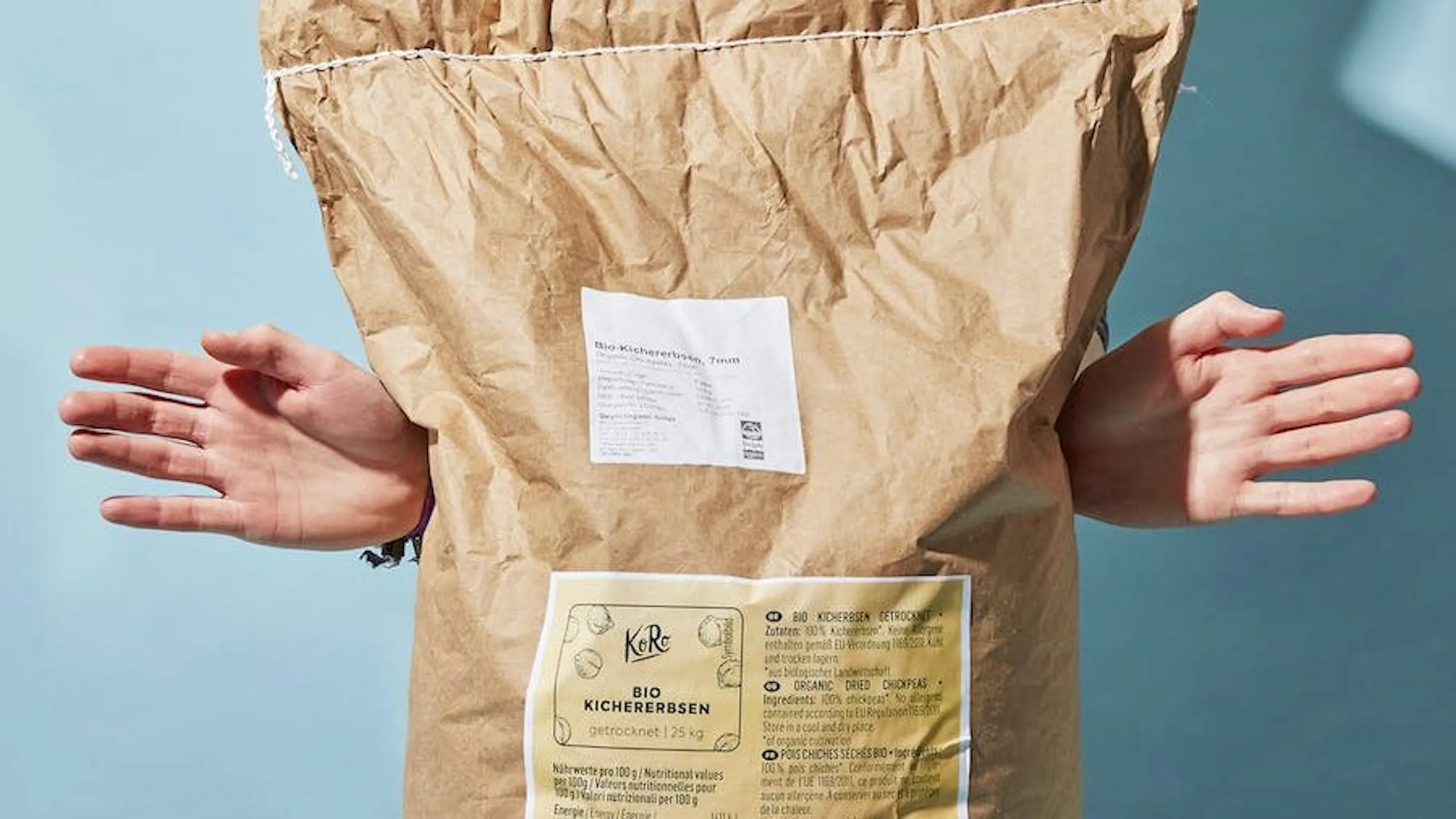 eine Person hält eine braune Papiertüte mit einem gelben Aufkleber darauf .
