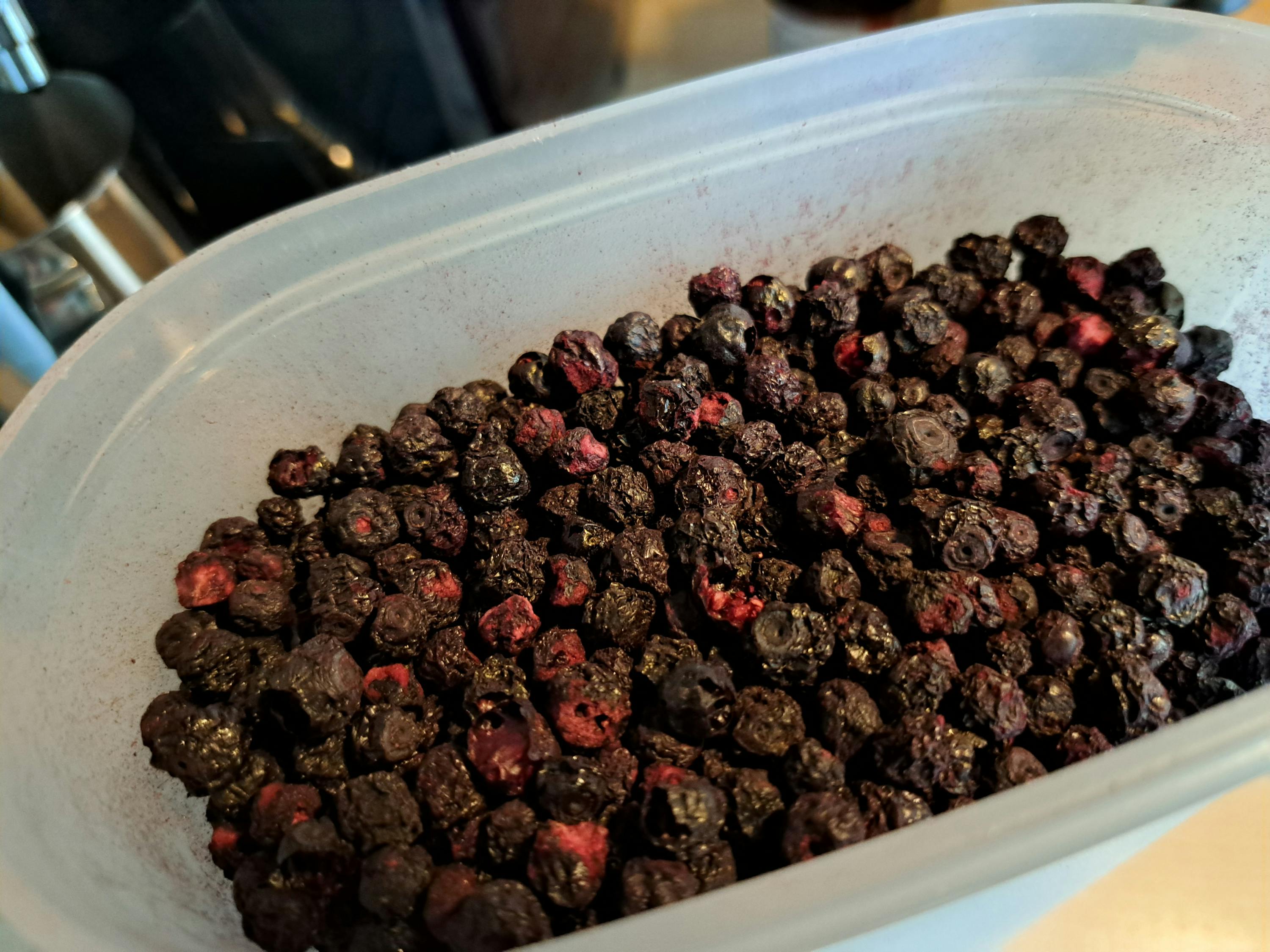 une boîte en plastique remplie de baies noires et rouges