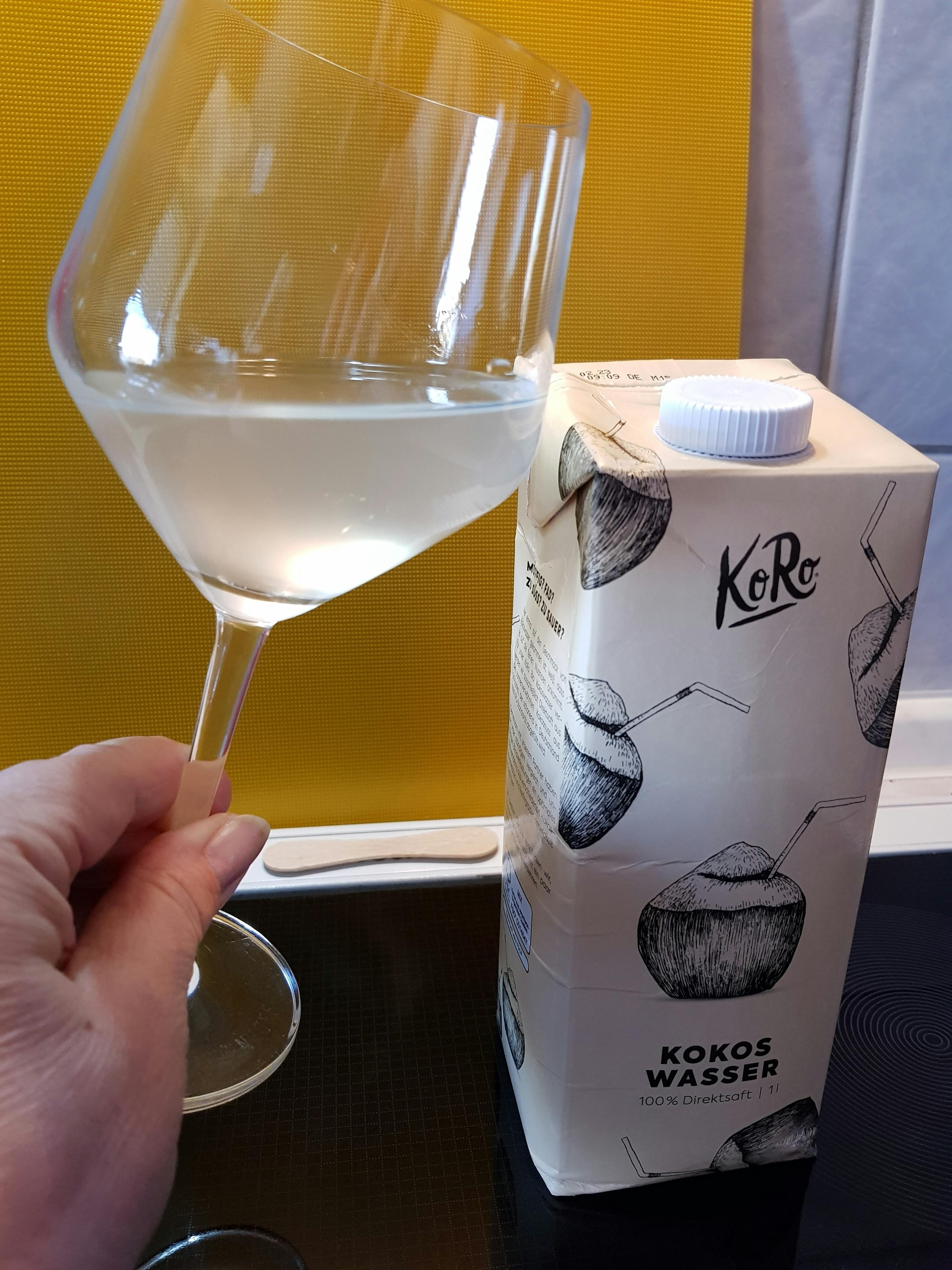 a carton of kokos wasser is next to a wine glass