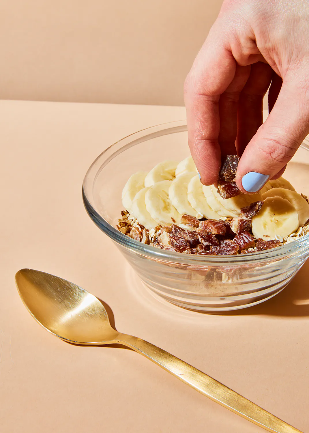 eine Person legt Bananenscheiben in eine Schüssel mit Müsli