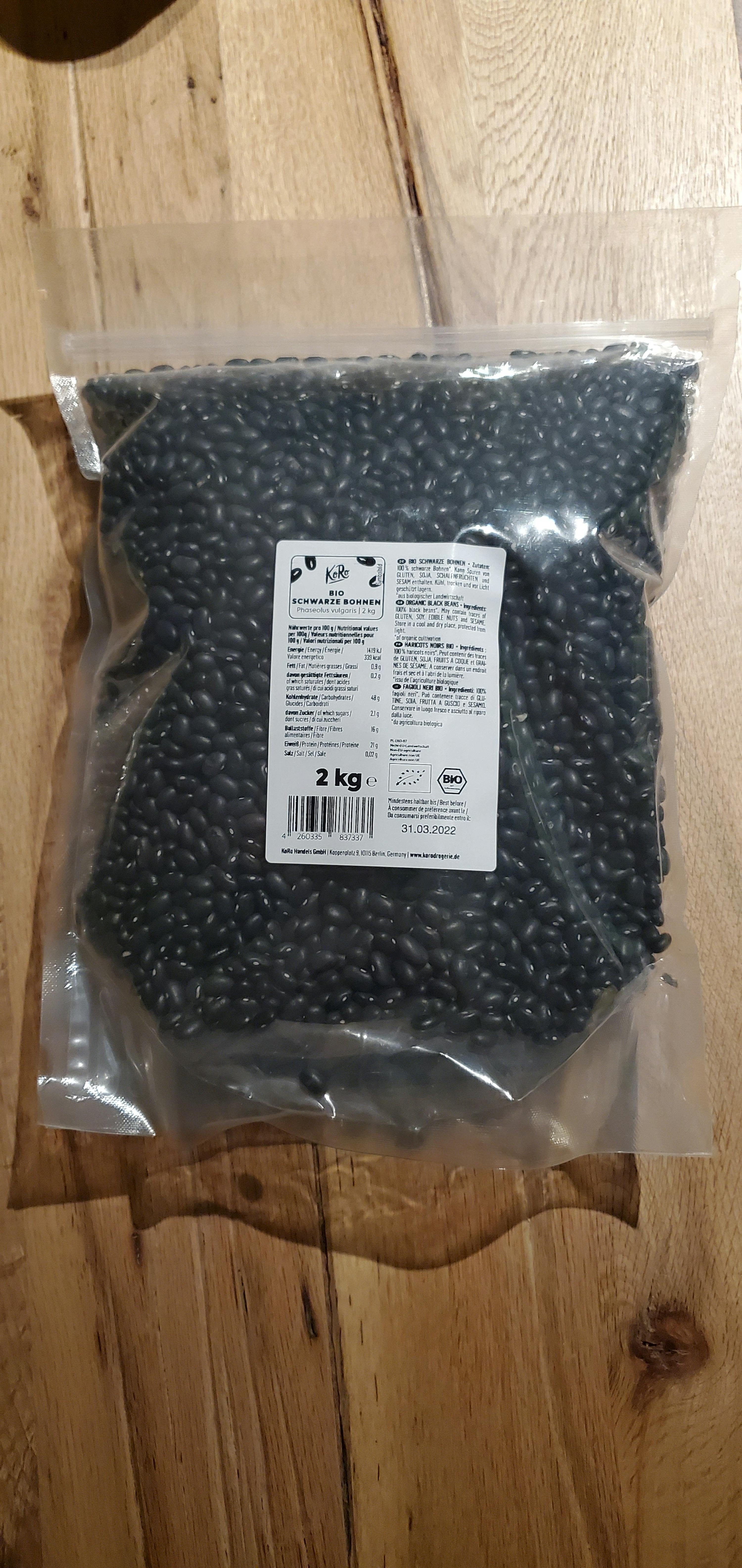 eine Plastiktüte mit schwarzen Bohnen steht auf einem Holztisch