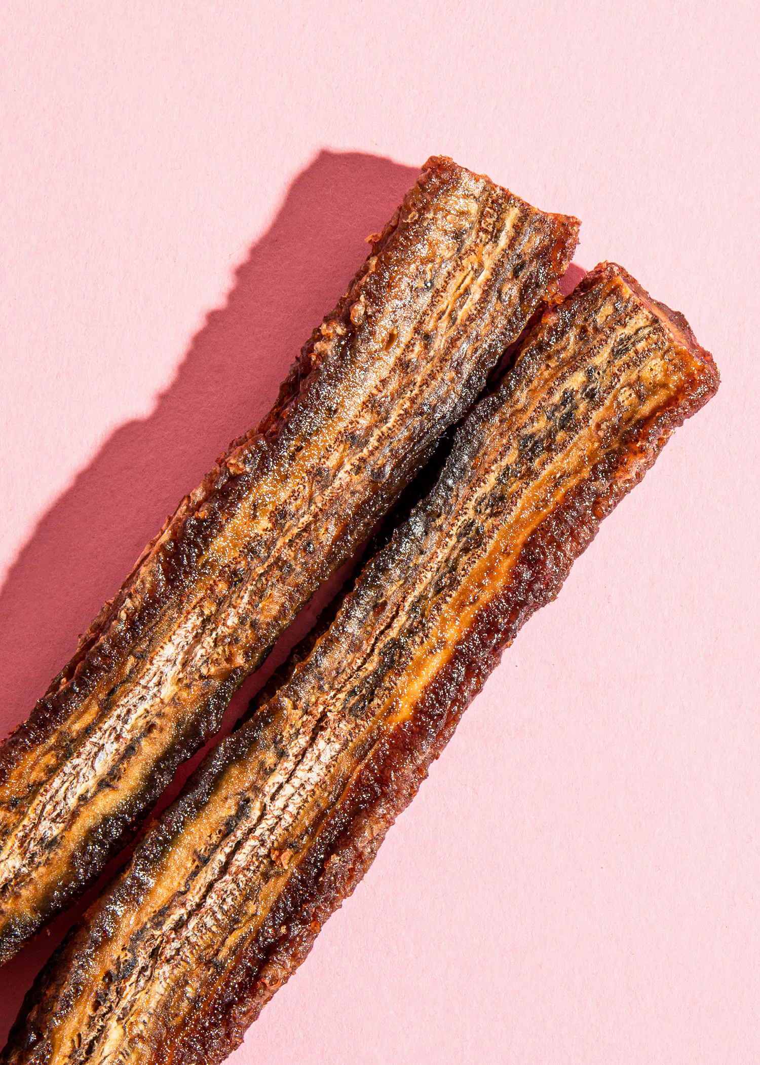 une paire de bâtonnets de viande sur fond rose