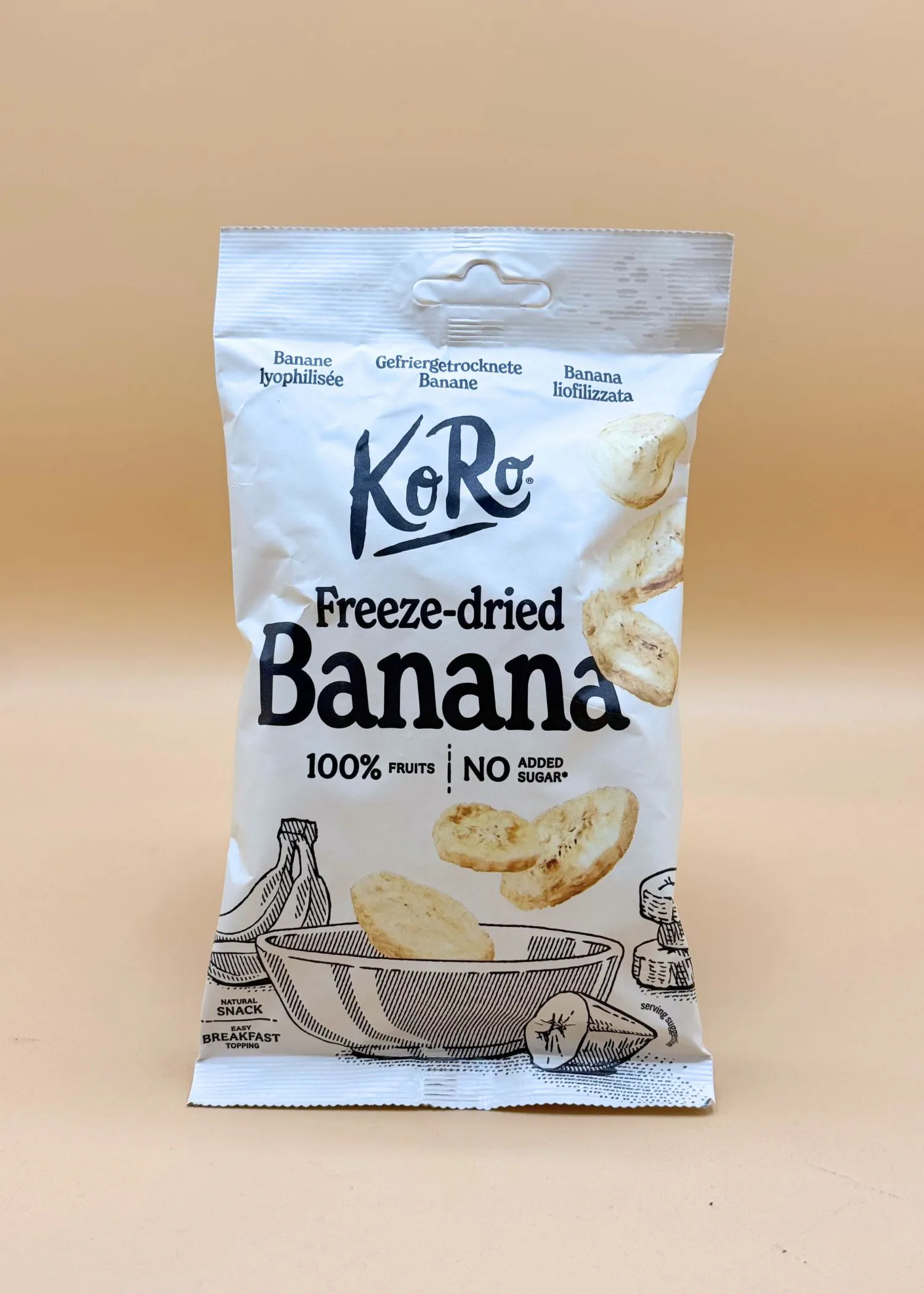 eine weiße verpackung von koro gefriergetrockneten bananen, die 100% früchte und keinen zugesetzten zucker enthält, mit abbildungen von bananen und bananenscheiben.