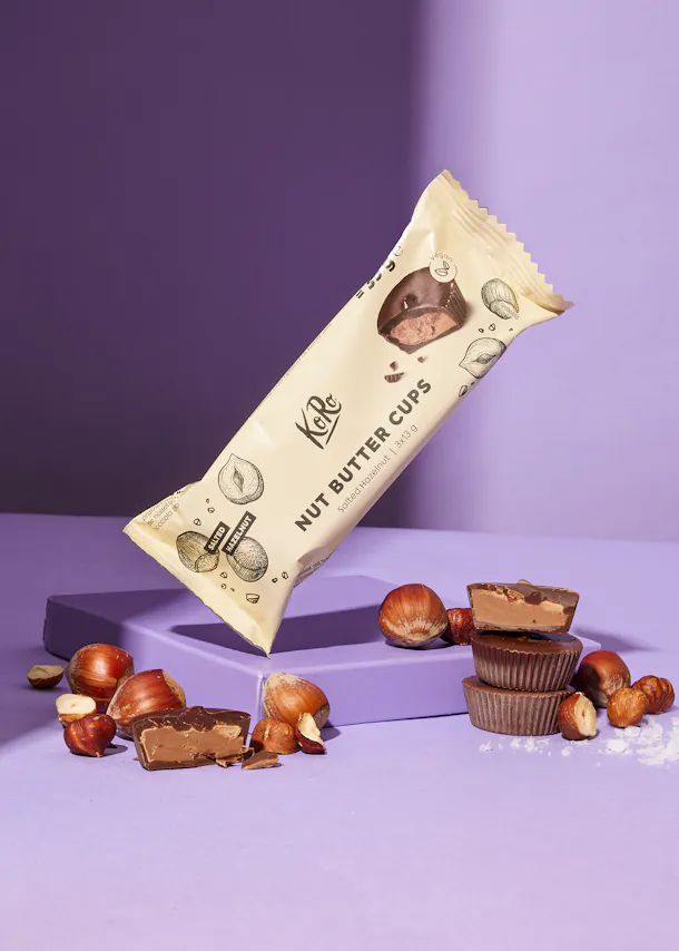 un paquet de tasses de beurre de noix avec des noisettes à côté