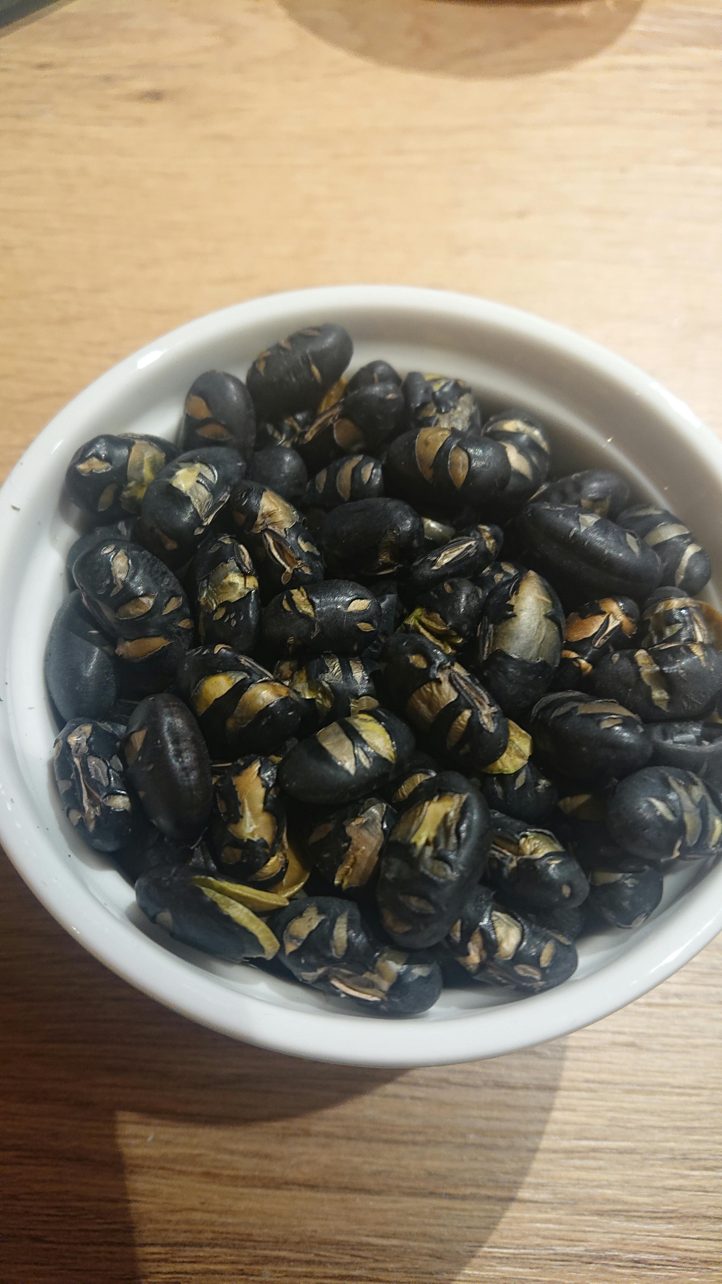 eine weiße Schüssel mit schwarzen Bohnen auf einem Tisch