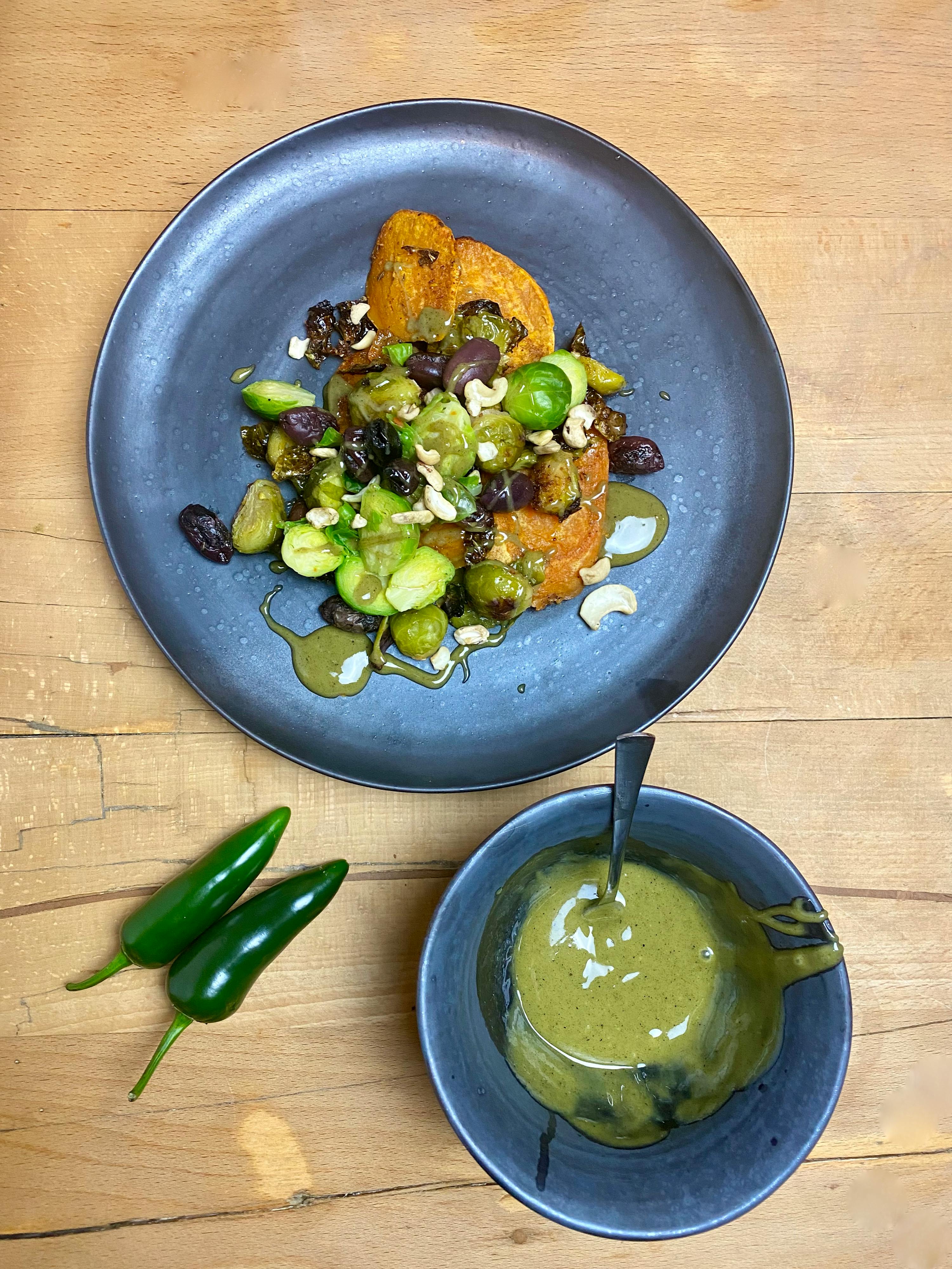 a bowl of green sauce sits next to a plate of food