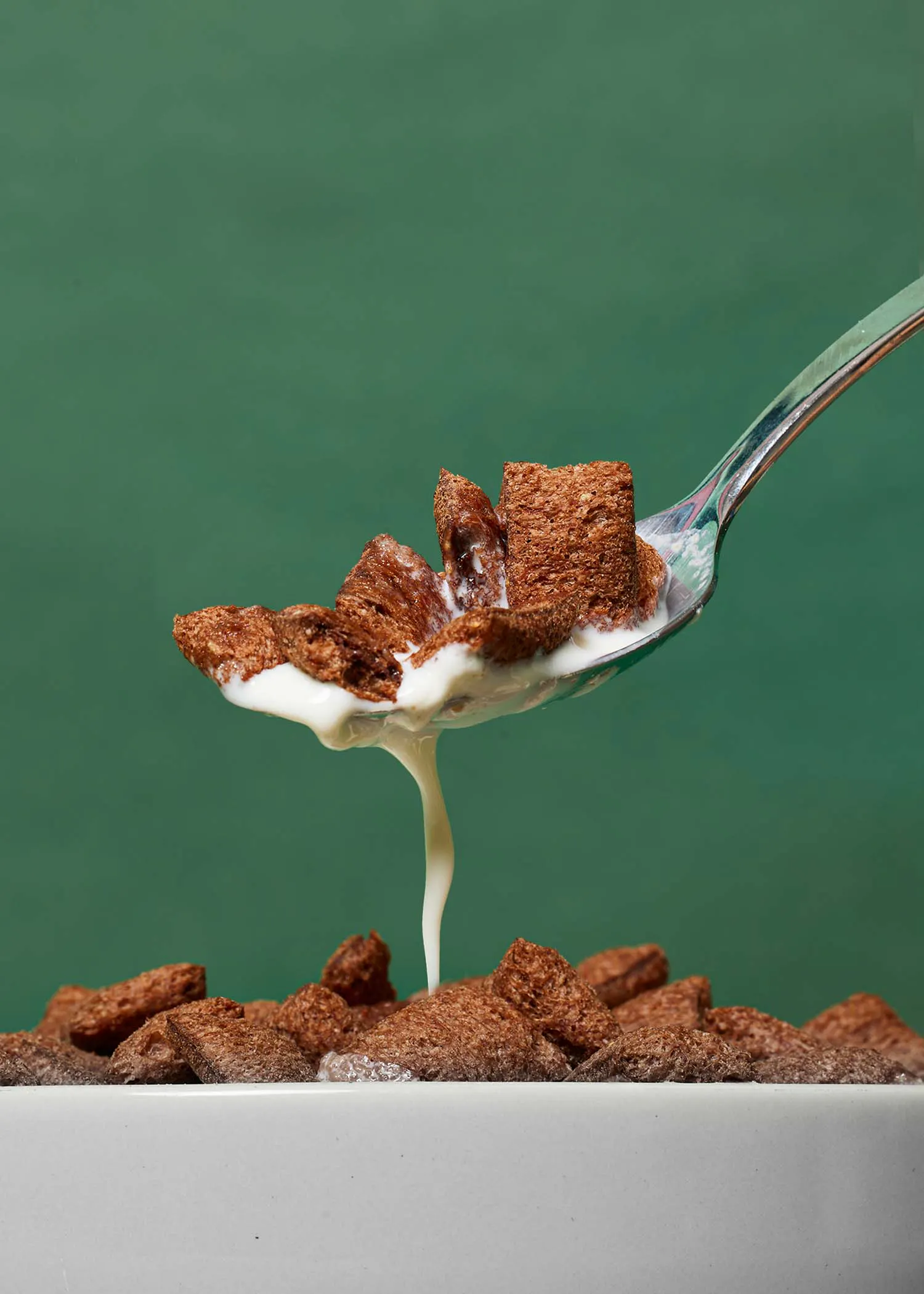 a spoonful of cereal is being poured over a bowl of cereal