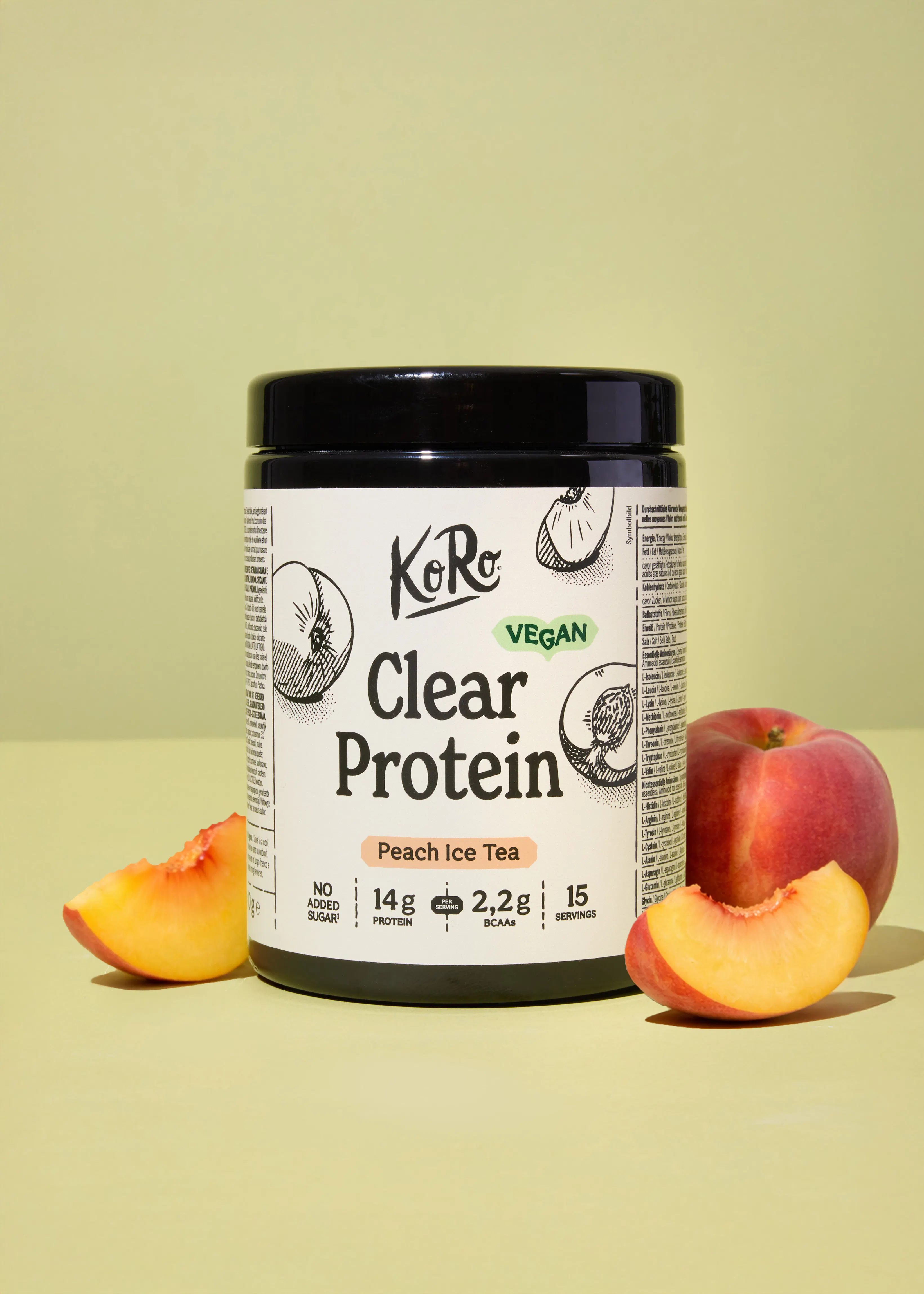 a black and white container of koro clear protein peach ice tea is displayed with a whole peach and two peach slices on a light green background.
