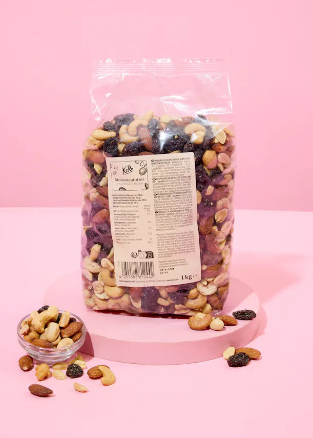 eine Tüte gemischte Nüsse auf einem rosa Tisch