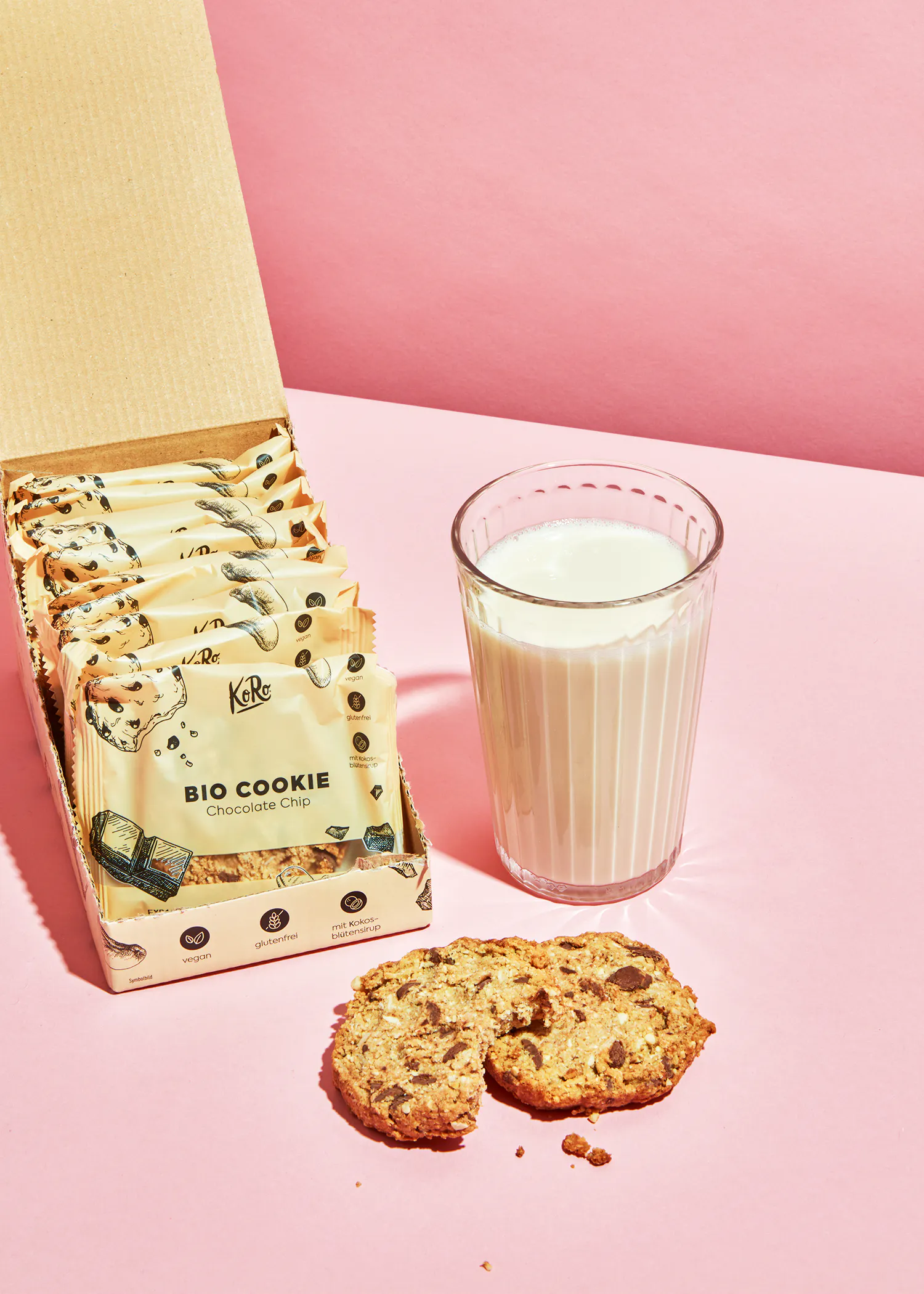une boîte de biscuits bio et un verre de lait sur une table rose