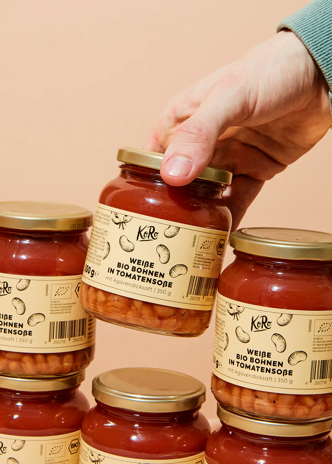 eine Person hält ein Glas weiße Bohnen in Tomatensoße