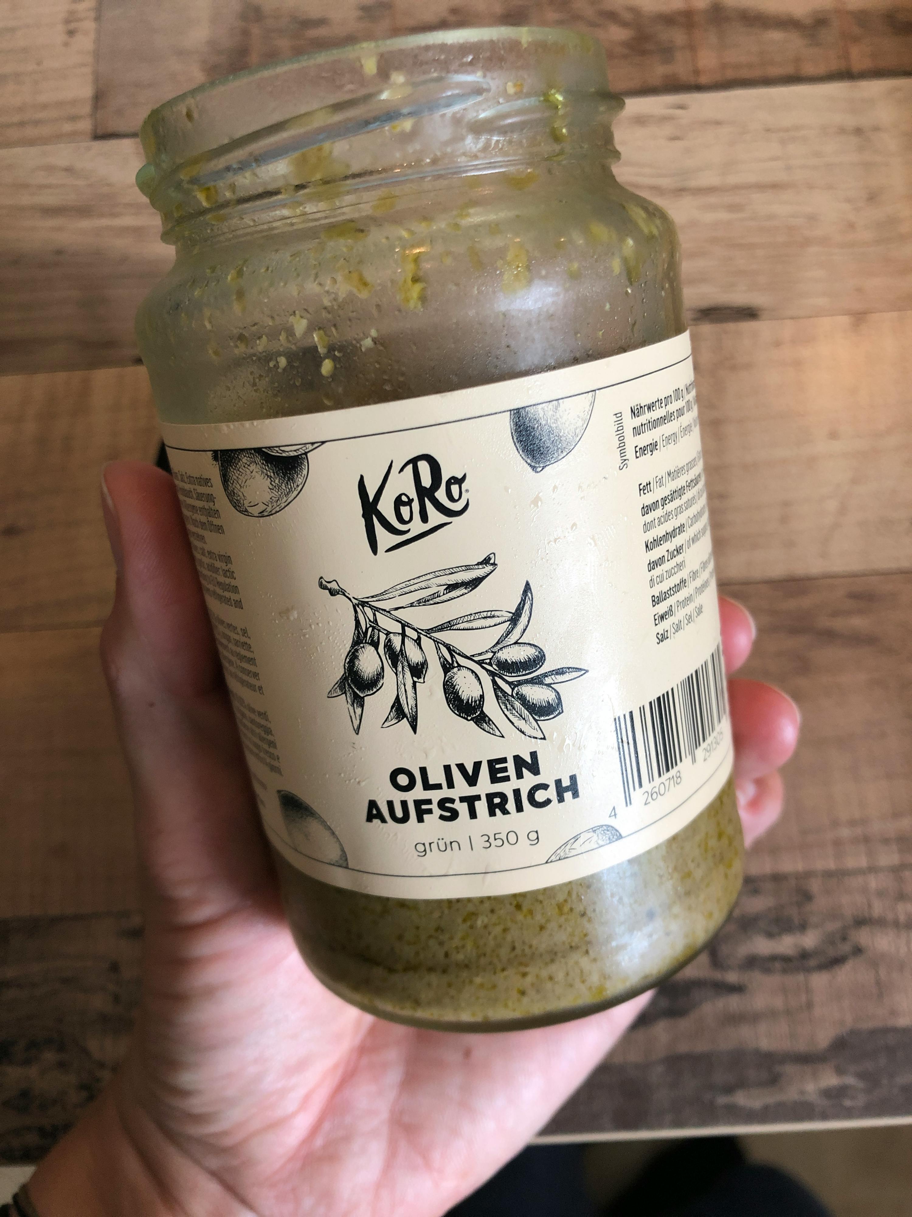 a person holding a jar of oliven aufstrich