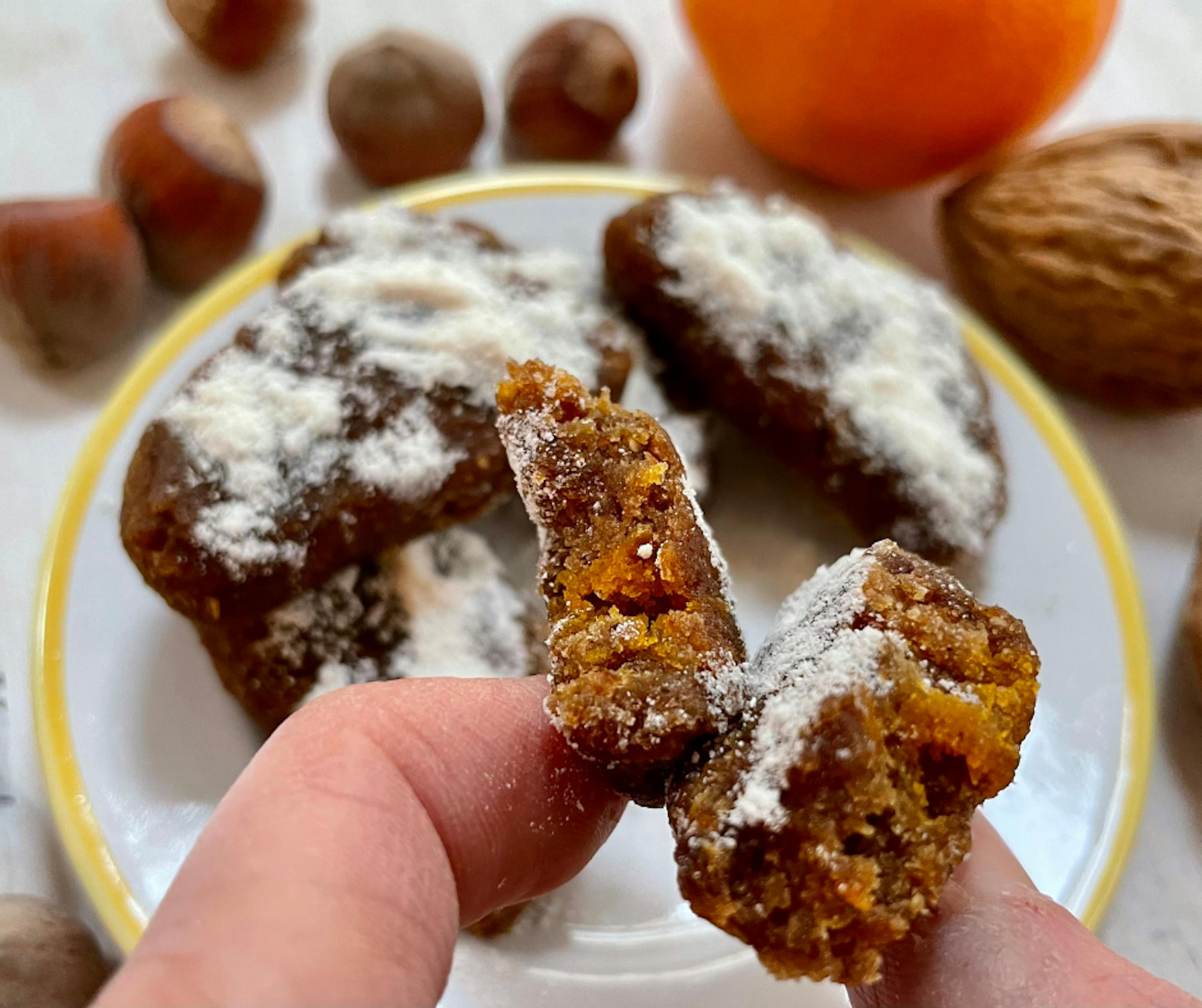 una persona tiene in mano un pezzo di cibo con zucchero a velo