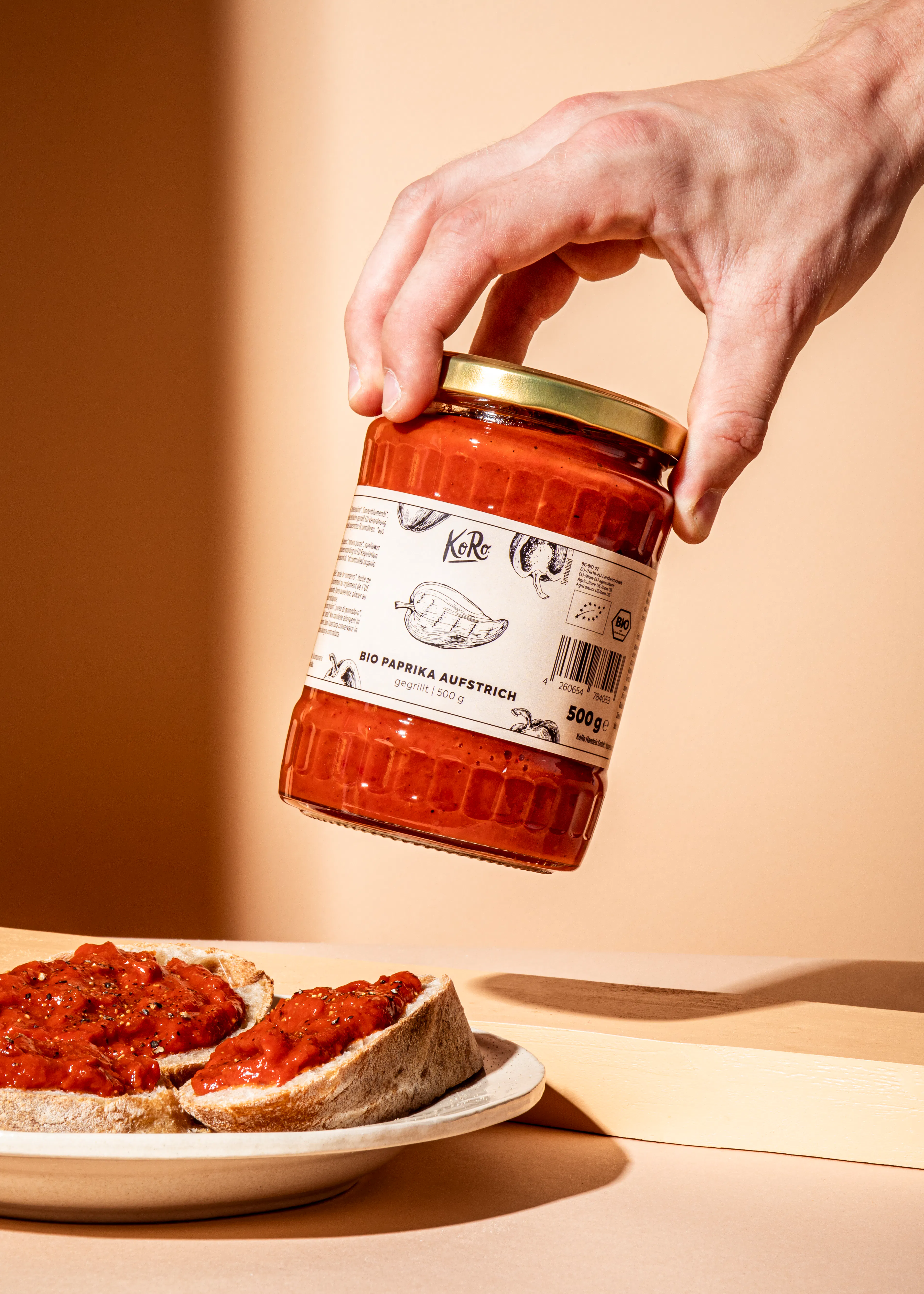 une personne tient une bouteille de paprika sur une assiette de pain