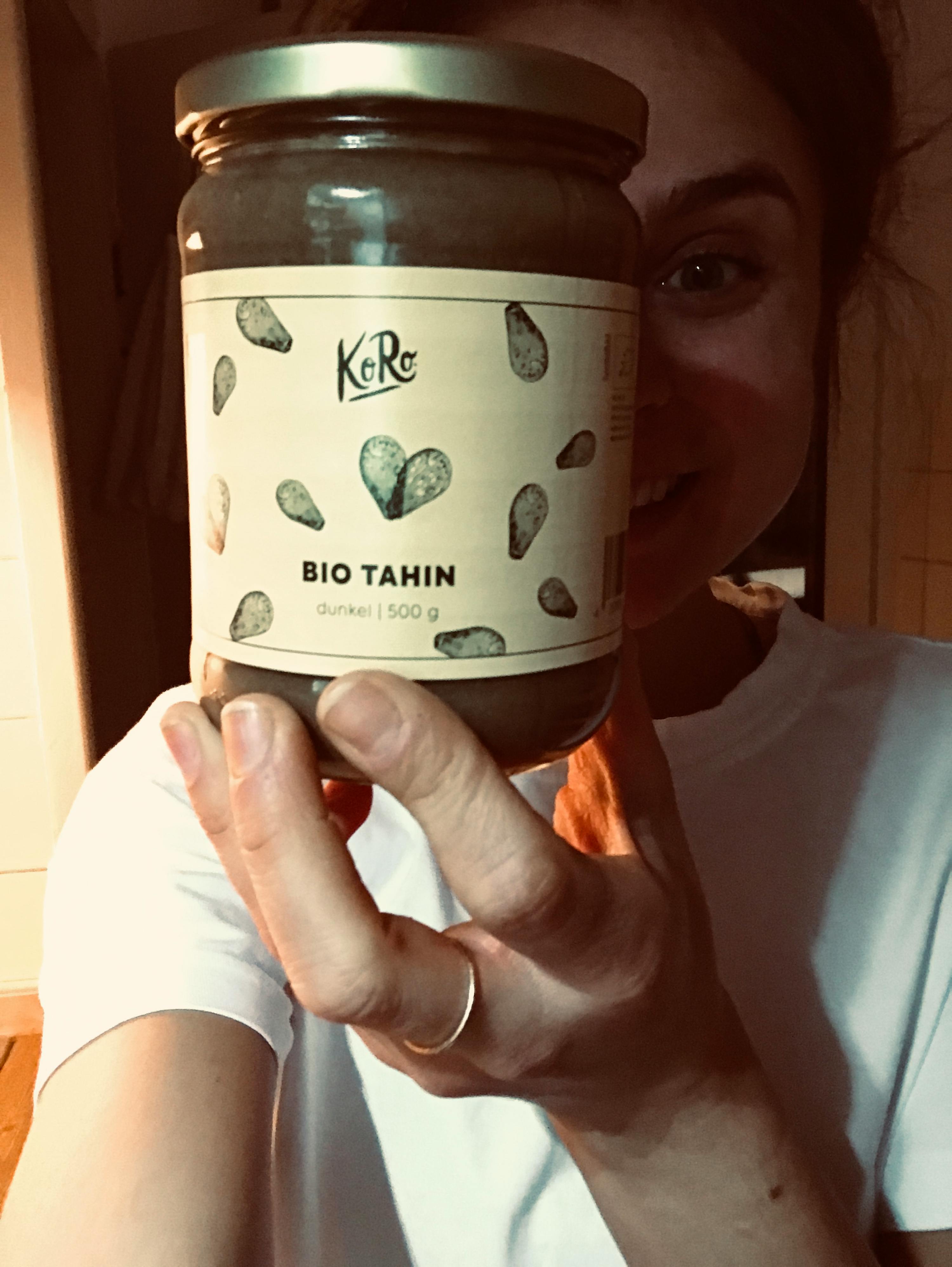 a woman is holding a jar of bio tahin