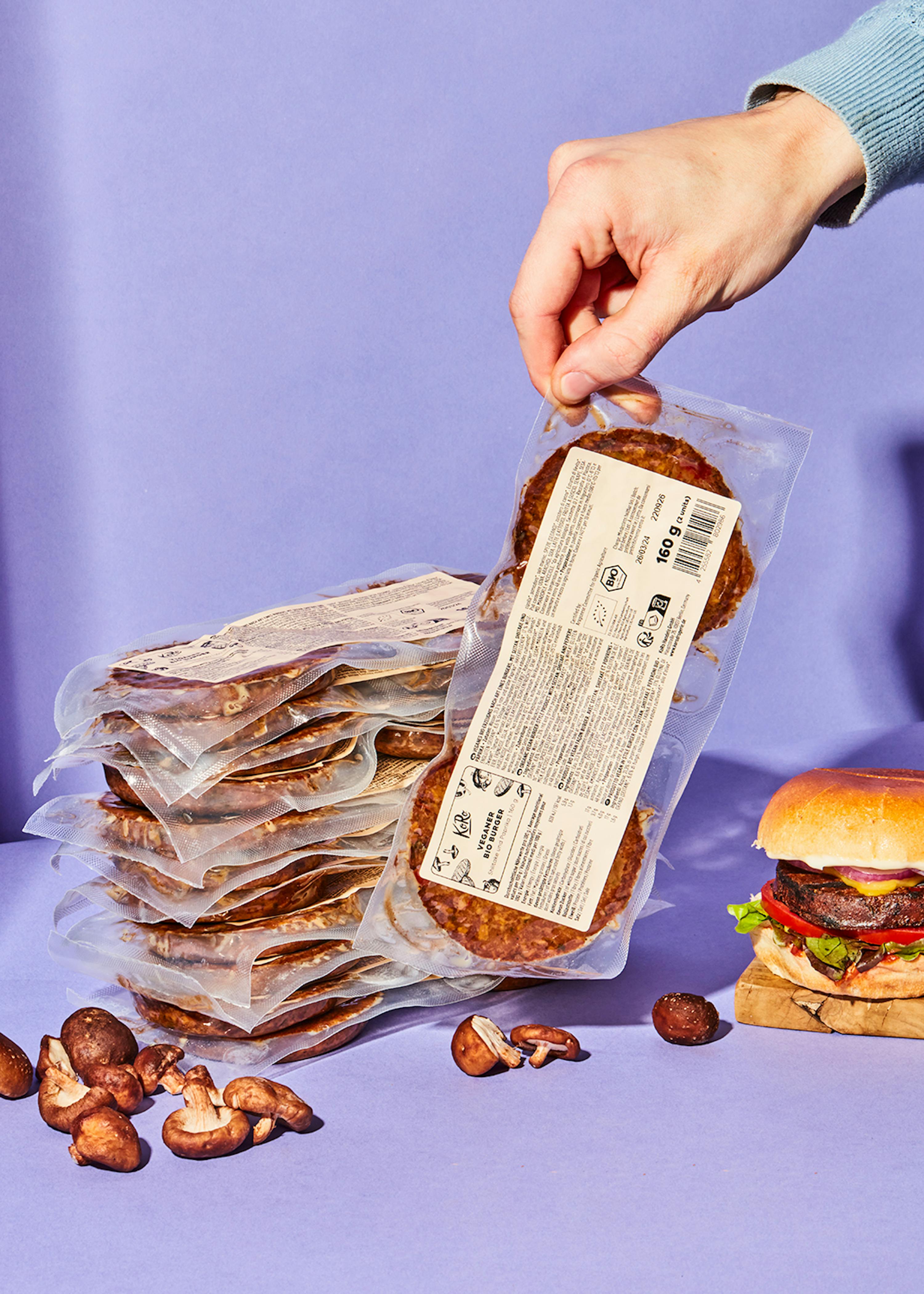 una persona sostiene un paquete de hamburguesas junto a una hamburguesa