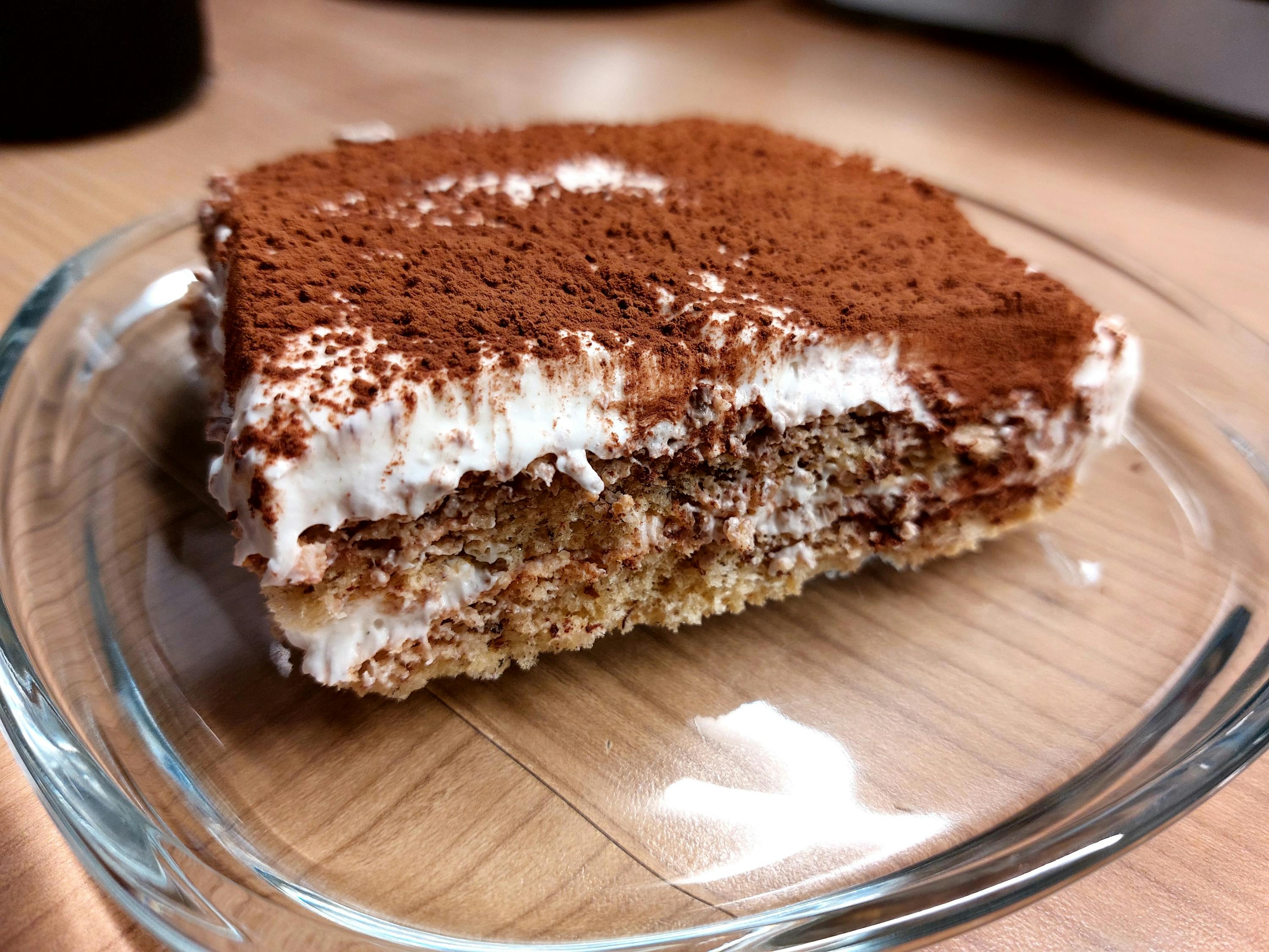 una fetta di torta tiramisù con panna montata e zucchero a velo