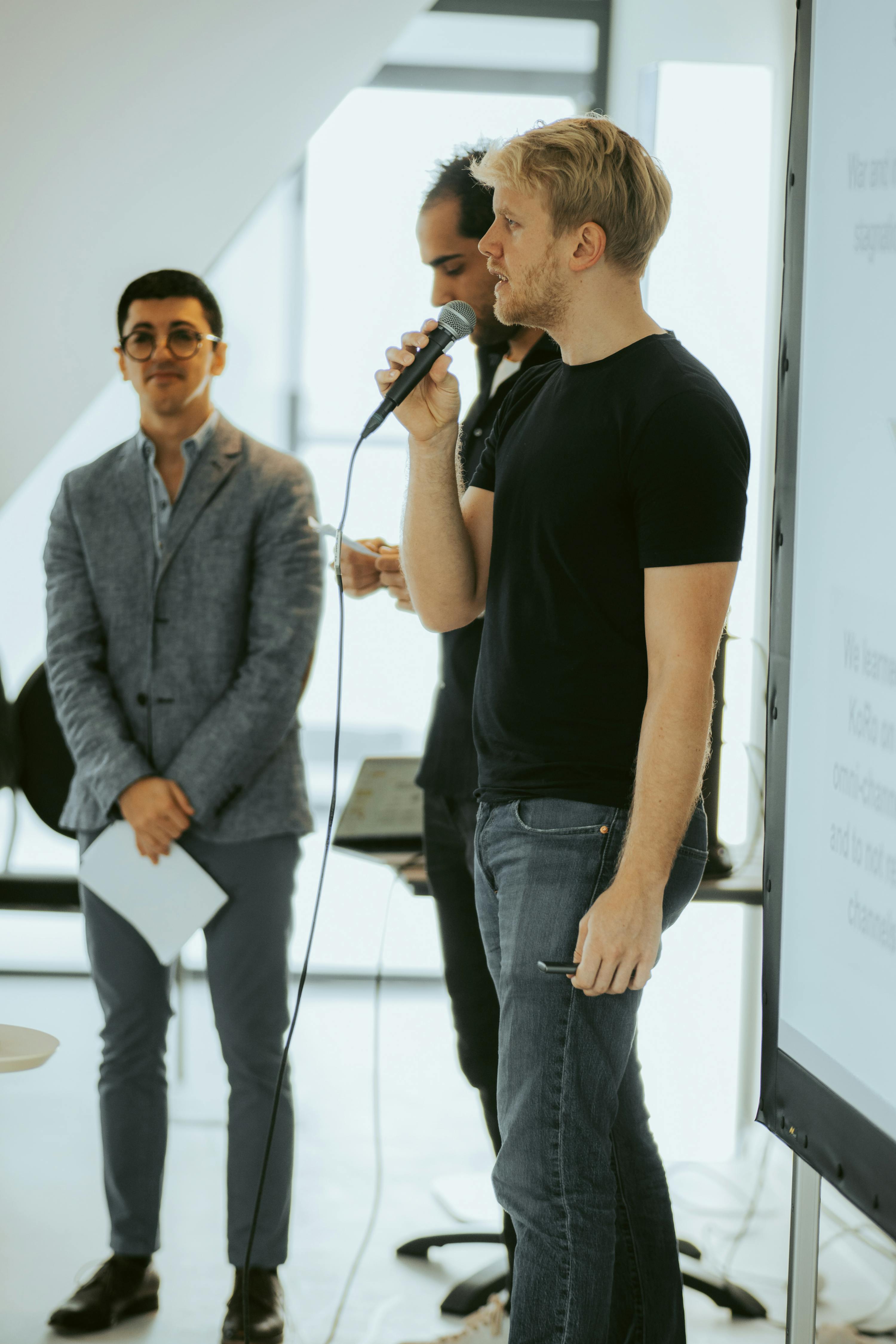 un uomo tiene in mano un microfono mentre due altri uomini guardano
