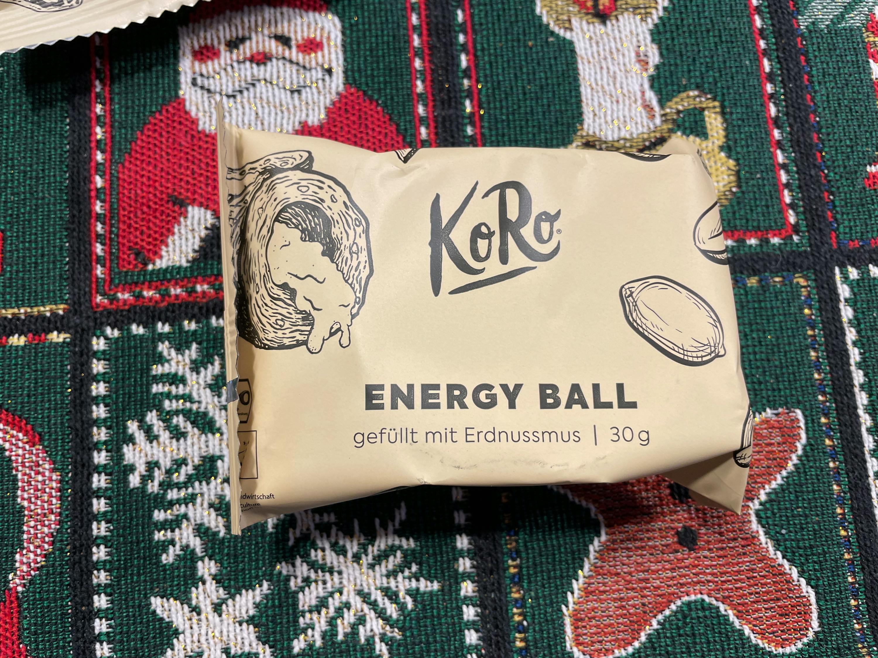 eine verpackte energy ball mit erdnussmus liegt auf einem weihnachtlichen tischtuch