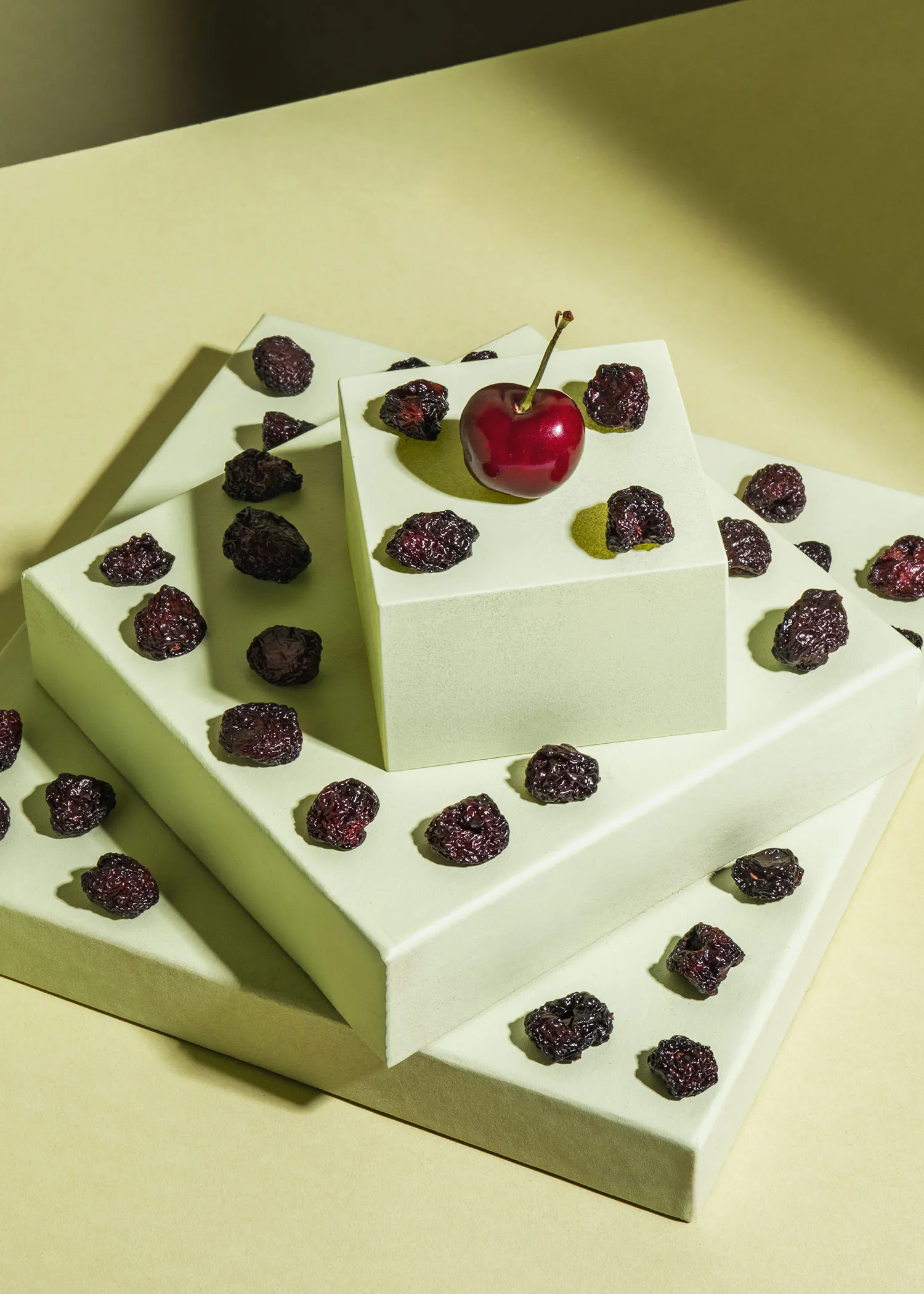 une cerise se trouve au sommet d' un carré blanc entouré de raisins secs