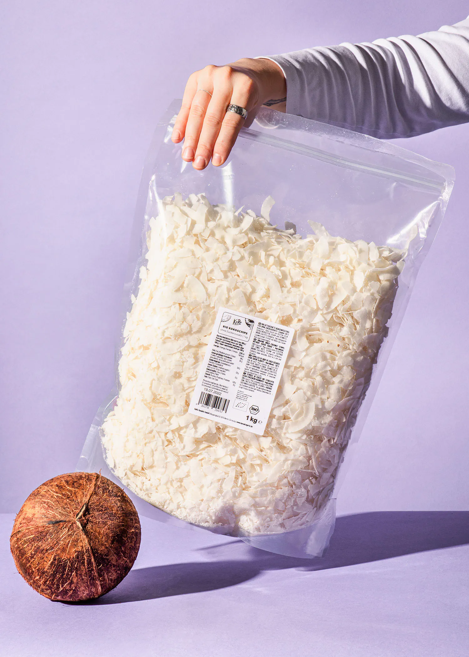 une personne tient un sac de noix de coco sur un fond violet
