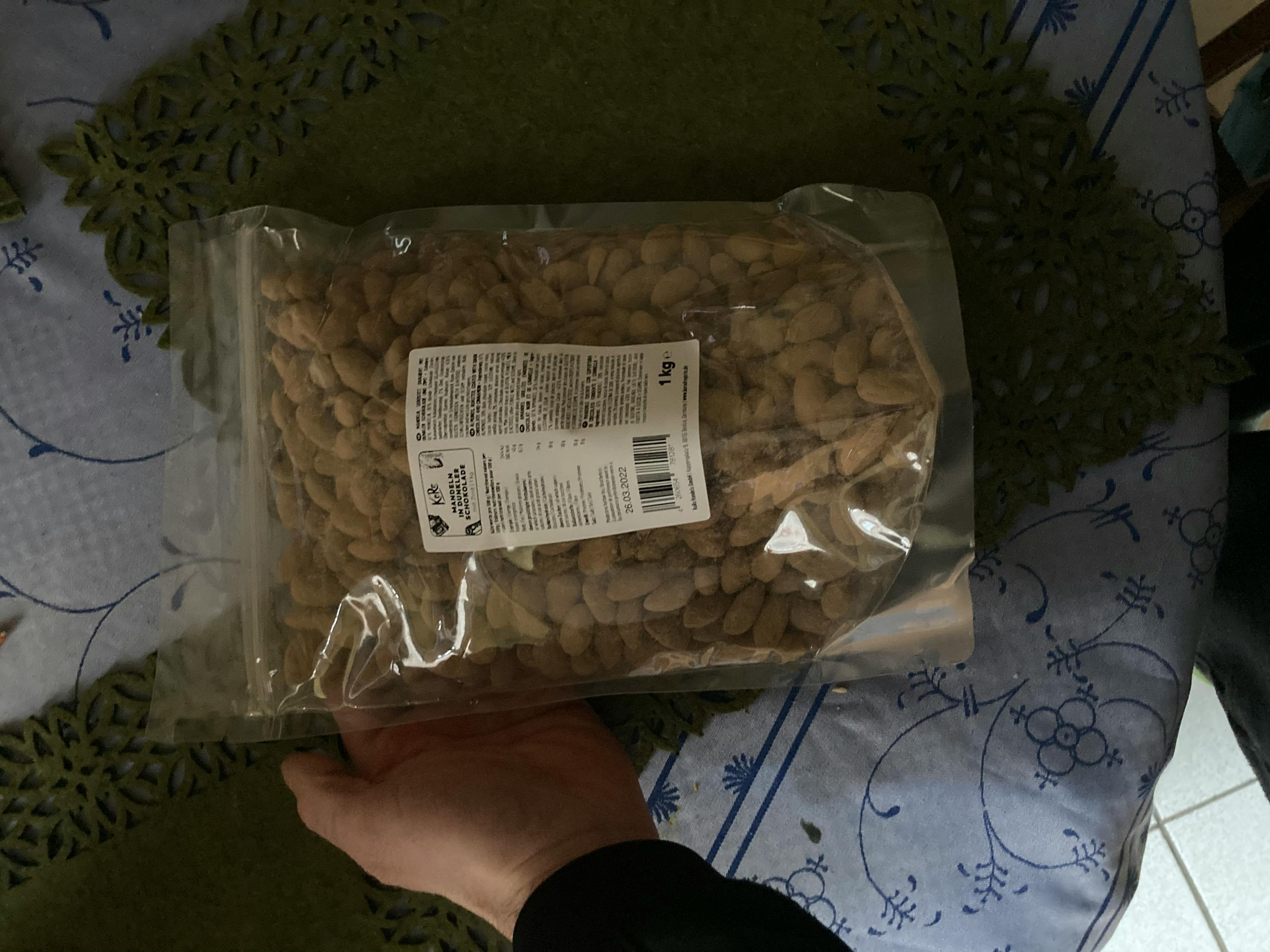 eine Person hält einen Plastikbeutel mit Erdnüssen in der Hand