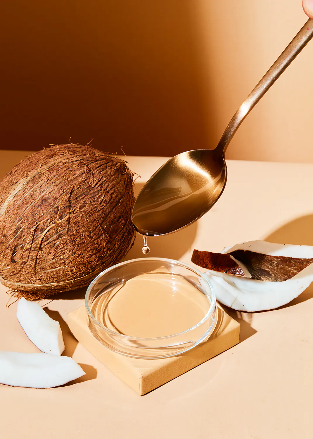 a person pouring coconut oil into a glass bowl