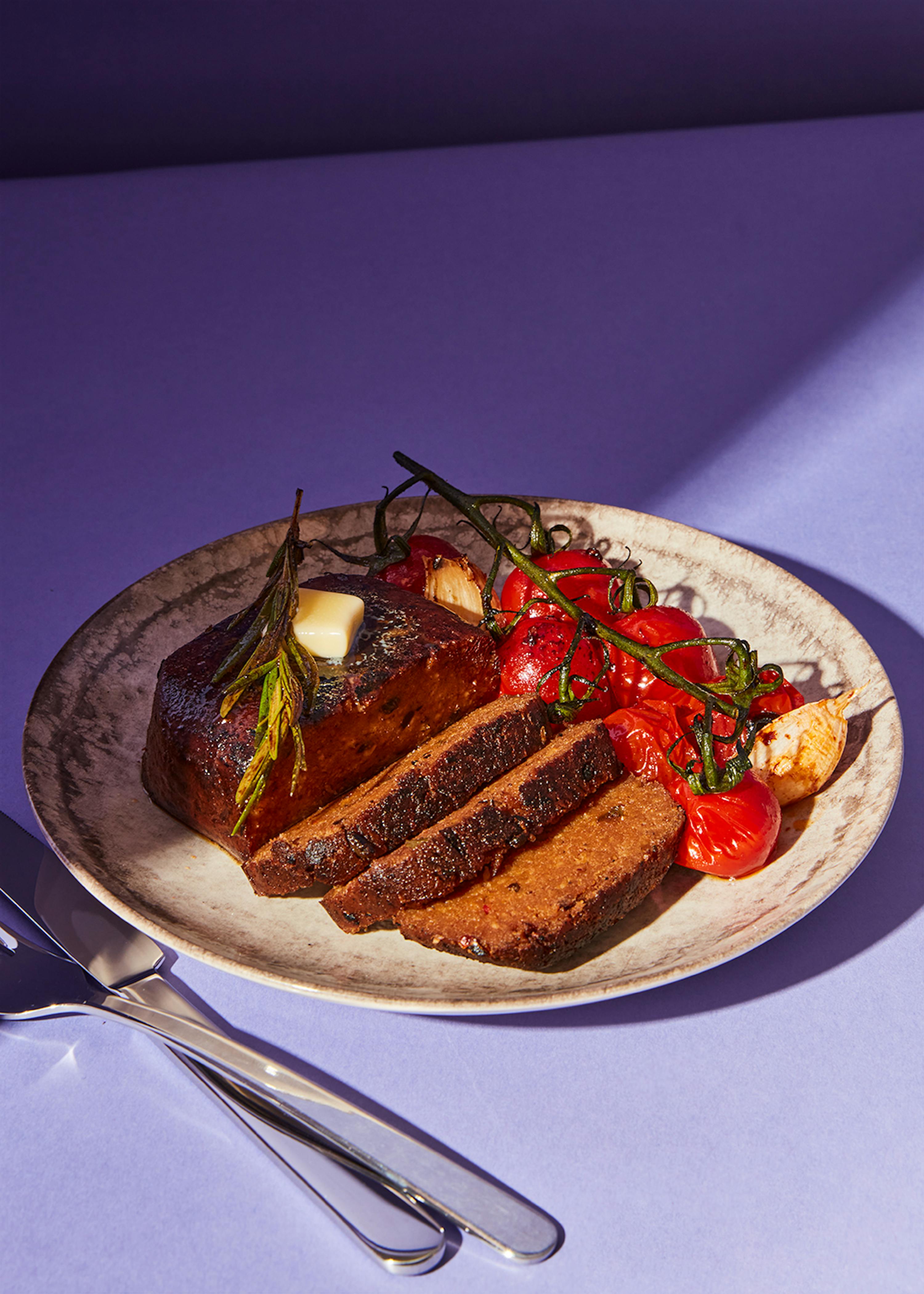 ein Teller mit einem Stück Fleisch und Tomaten darauf