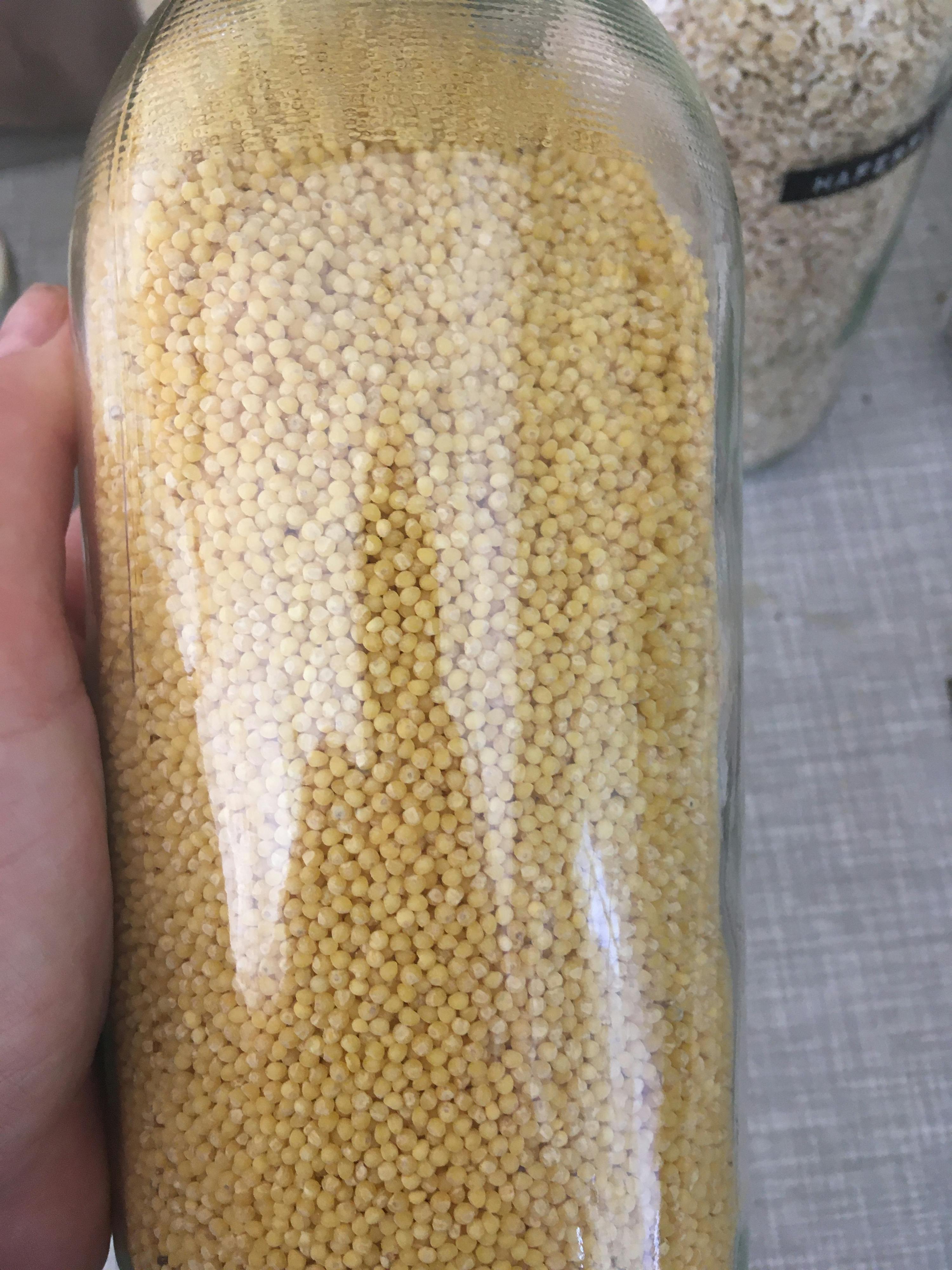 a person is holding a jar of grains in their hand