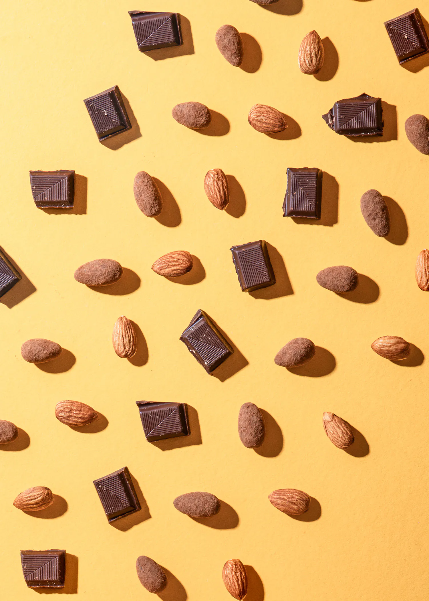 des morceaux de chocolat et des amandes sur un fond jaune