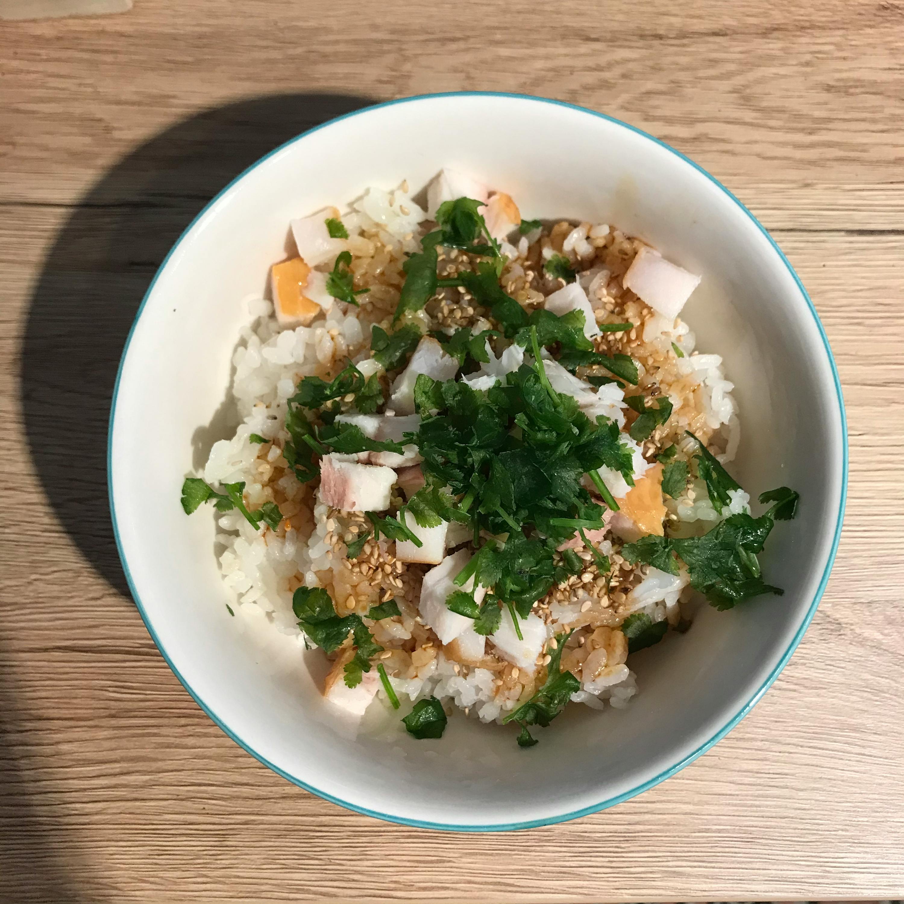 a bowl of rice with meat and parsley on a wooden table