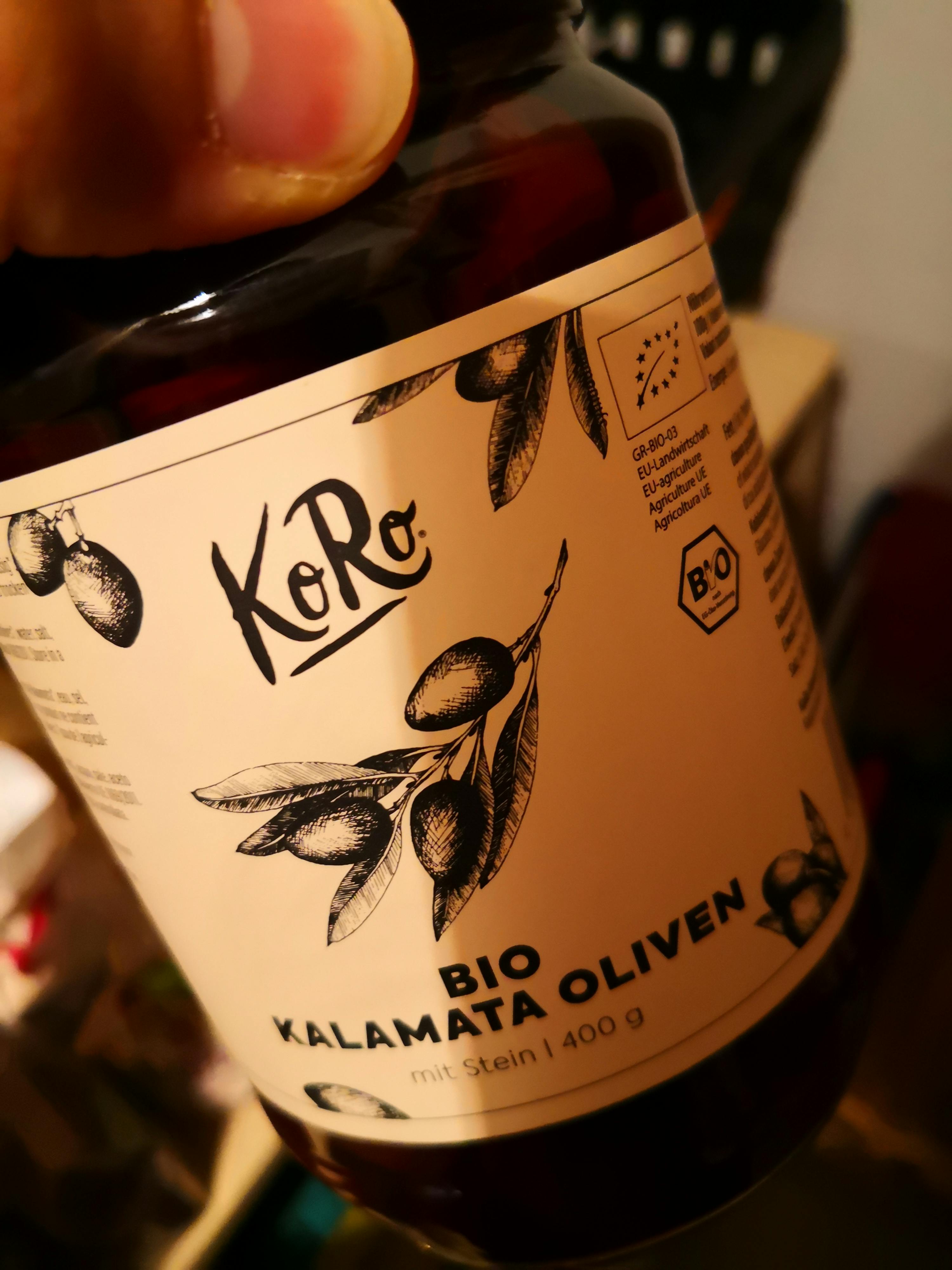 eine Person hält eine Flasche bio kalamata Oliven