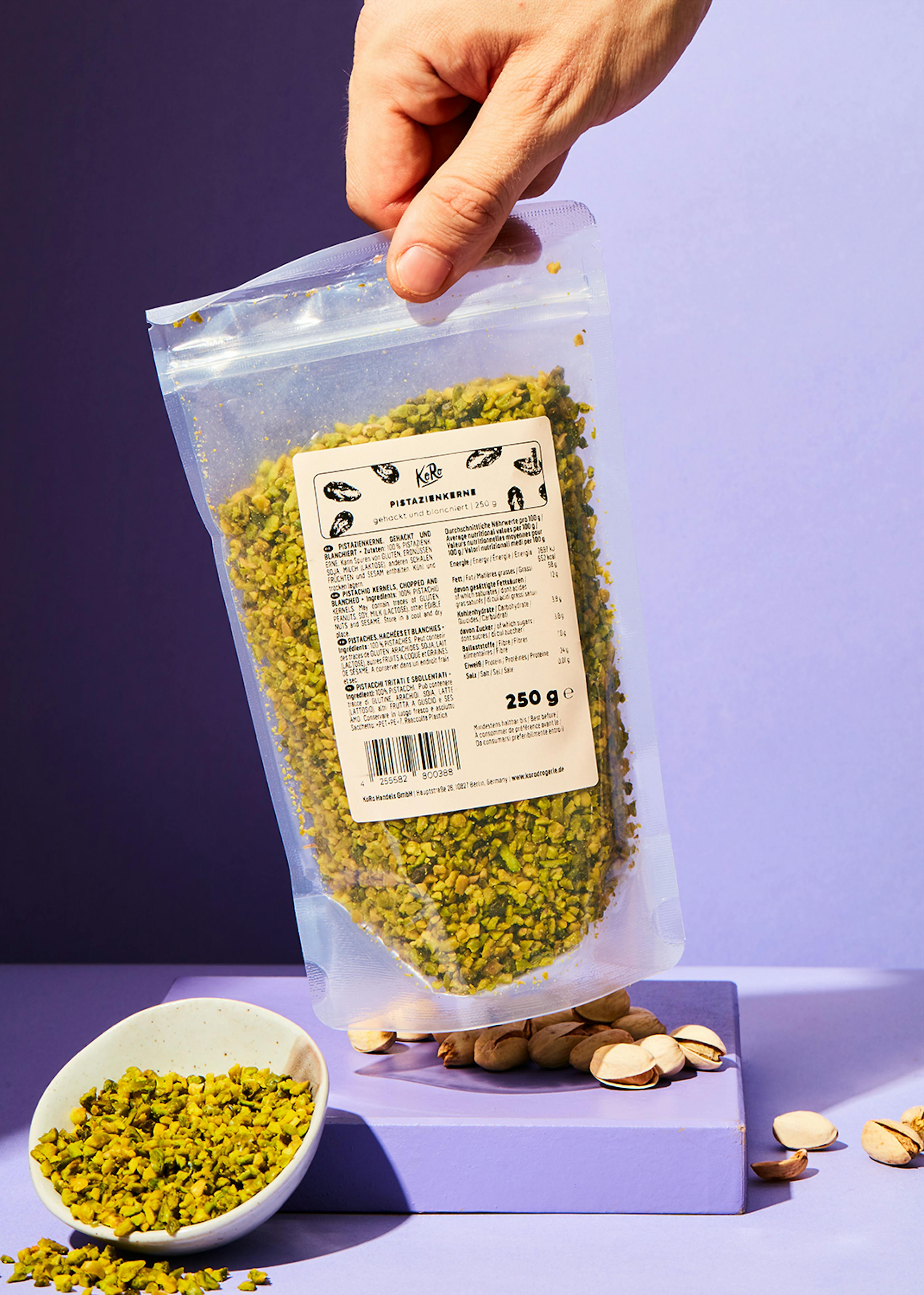 eine Person hält eine Plastiktüte mit pistazienkernen in der Hand