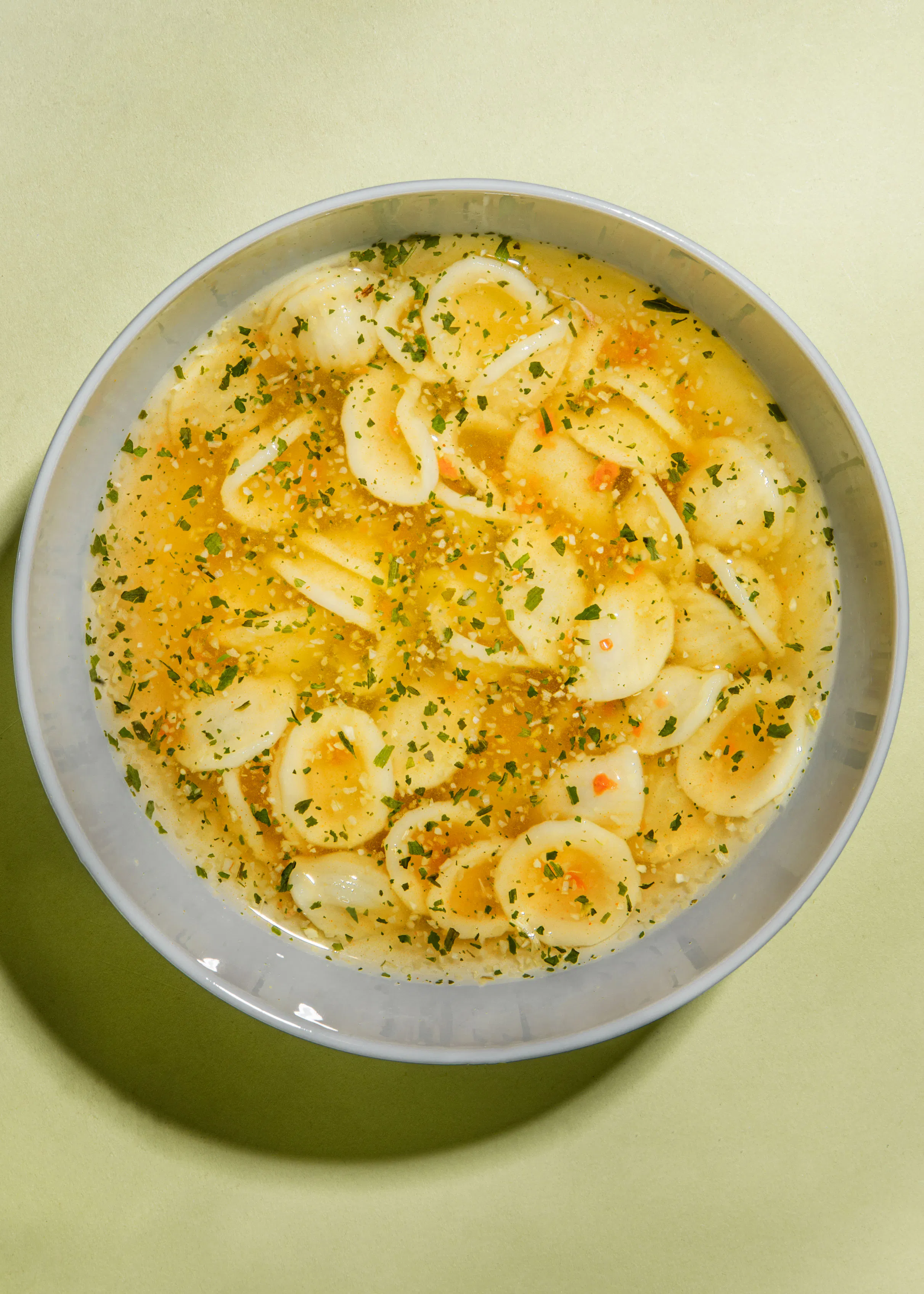 a bowl of soup with noodles and carrots on a table